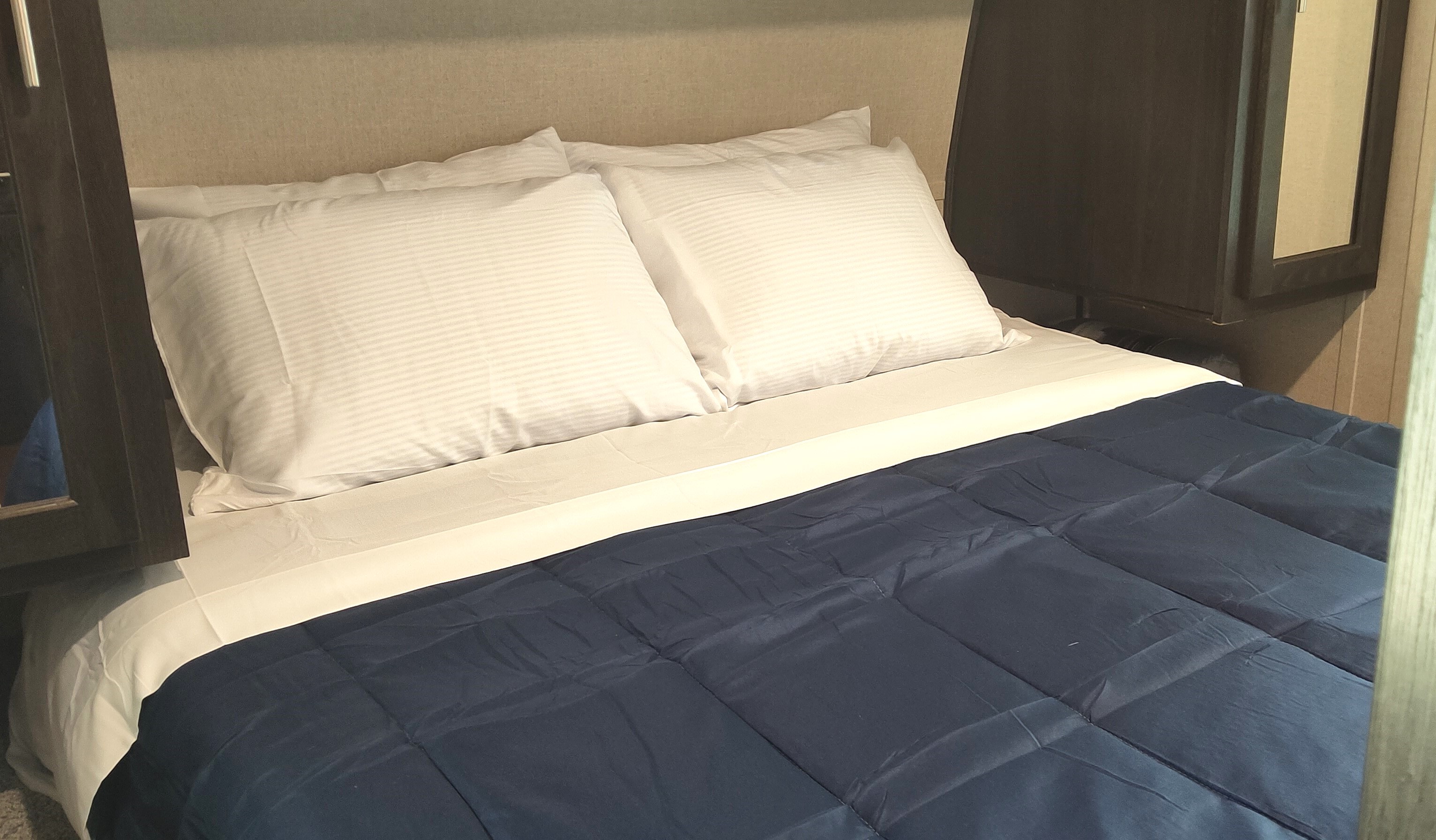 Comfortable bed with white sheets & blue comforter in an RV rental bedroom, perfect for restful travel.. Forest River Nitro Xlr 2019