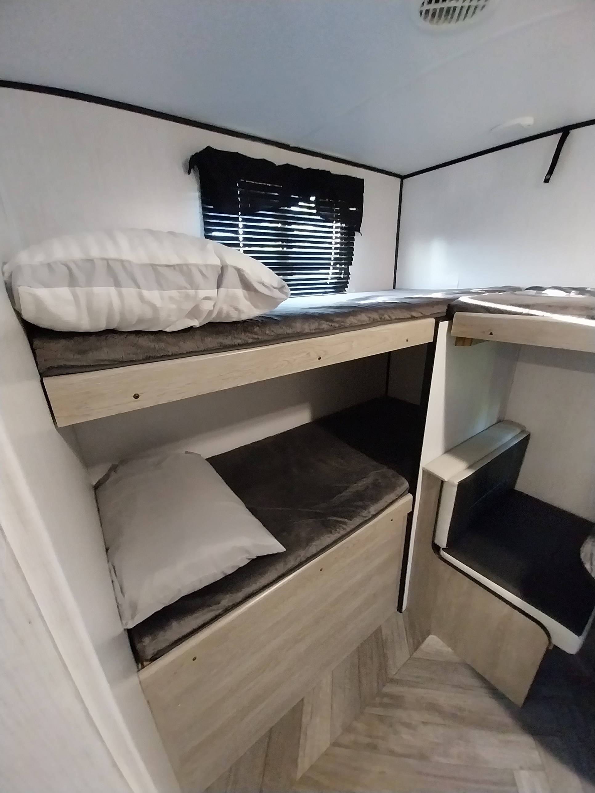 Cozy RV rental interior showcasing a twin over twin bunk bed layout with a convenient seating area.. Heartland RVs Prowler 2023