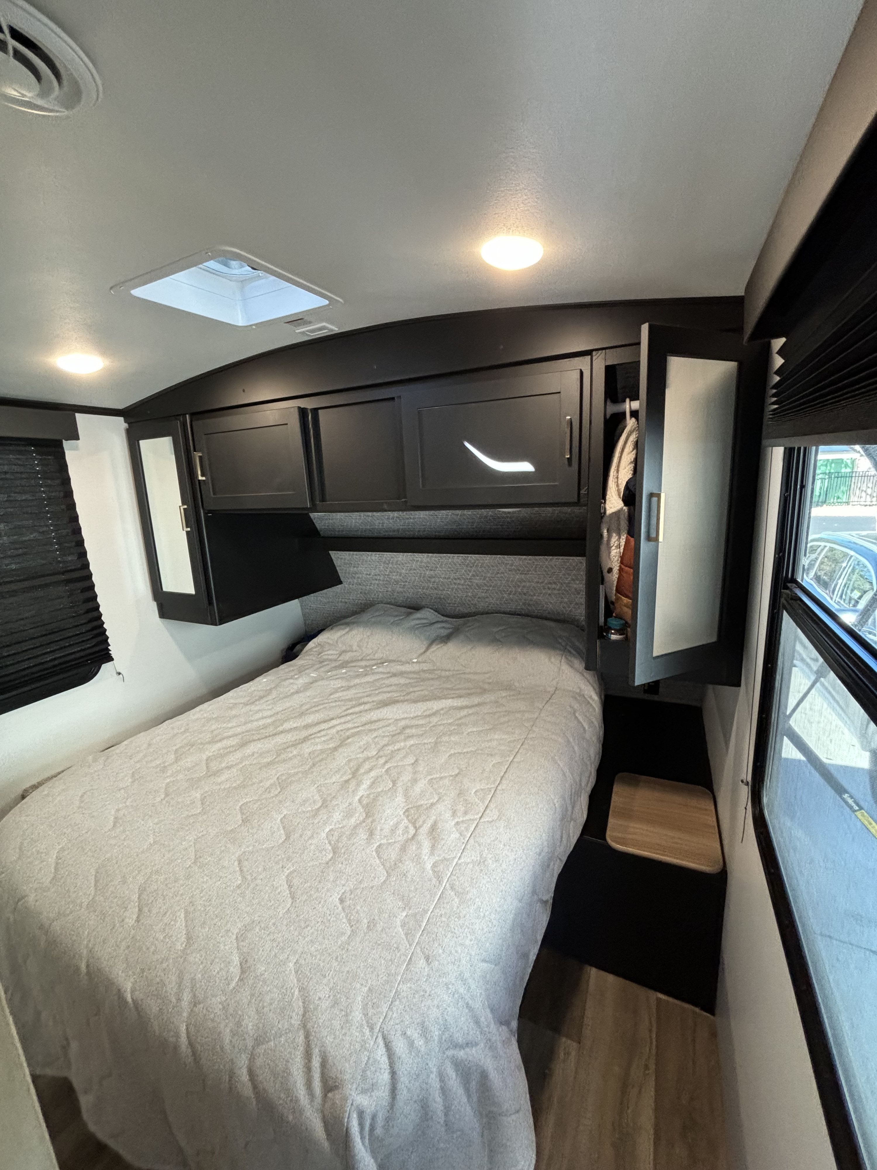 Compact RV rental bedroom with a comfy bed, overhead storage, and windows, offering a cozy space for travel.. Keystone RV Outback Ultra-Lite 2021