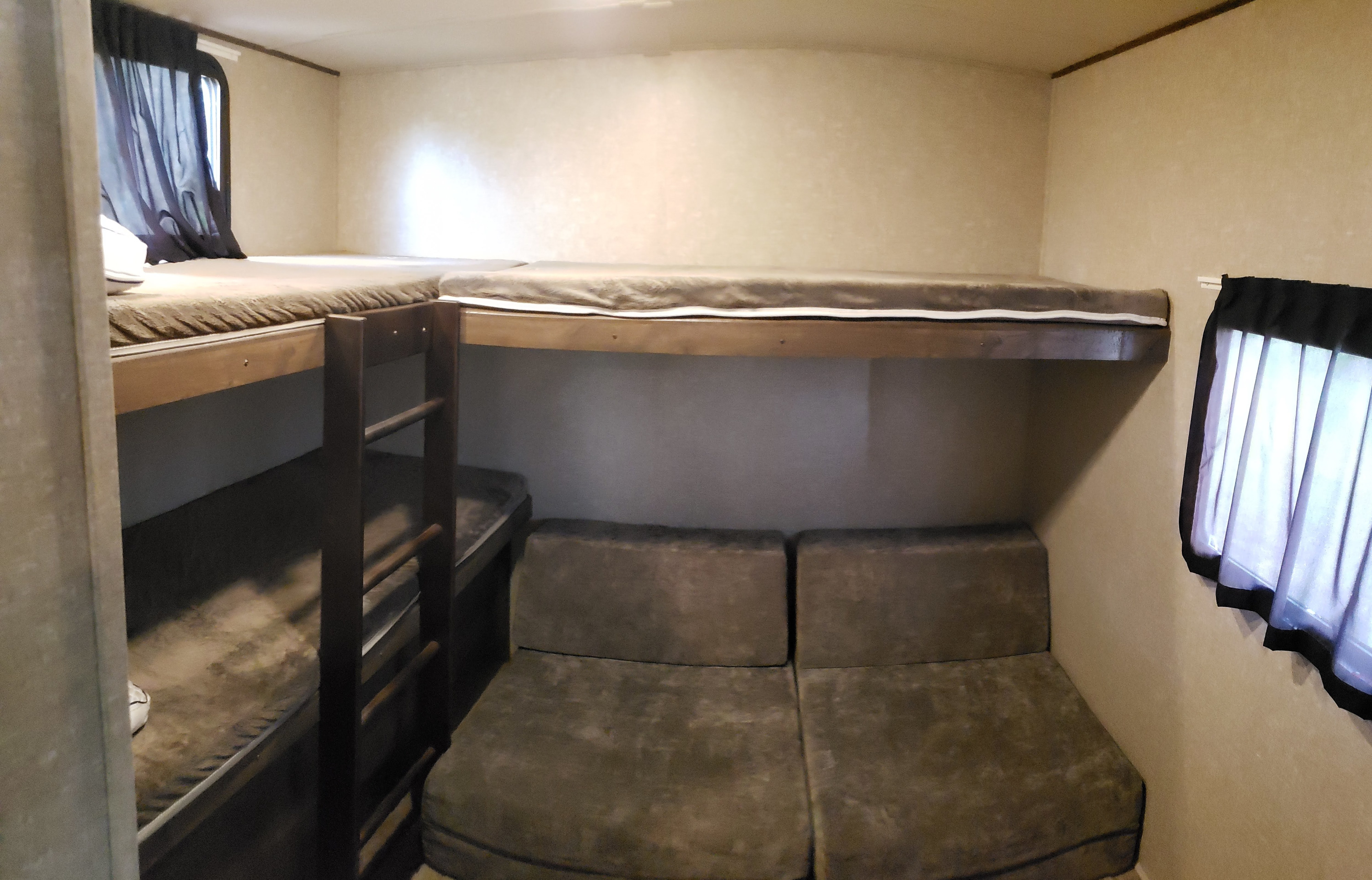 RV rental bunk room: upper and lower bunk beds, a ladder, and a convertible seating area below, with windows.. Forest River Vibe 2019