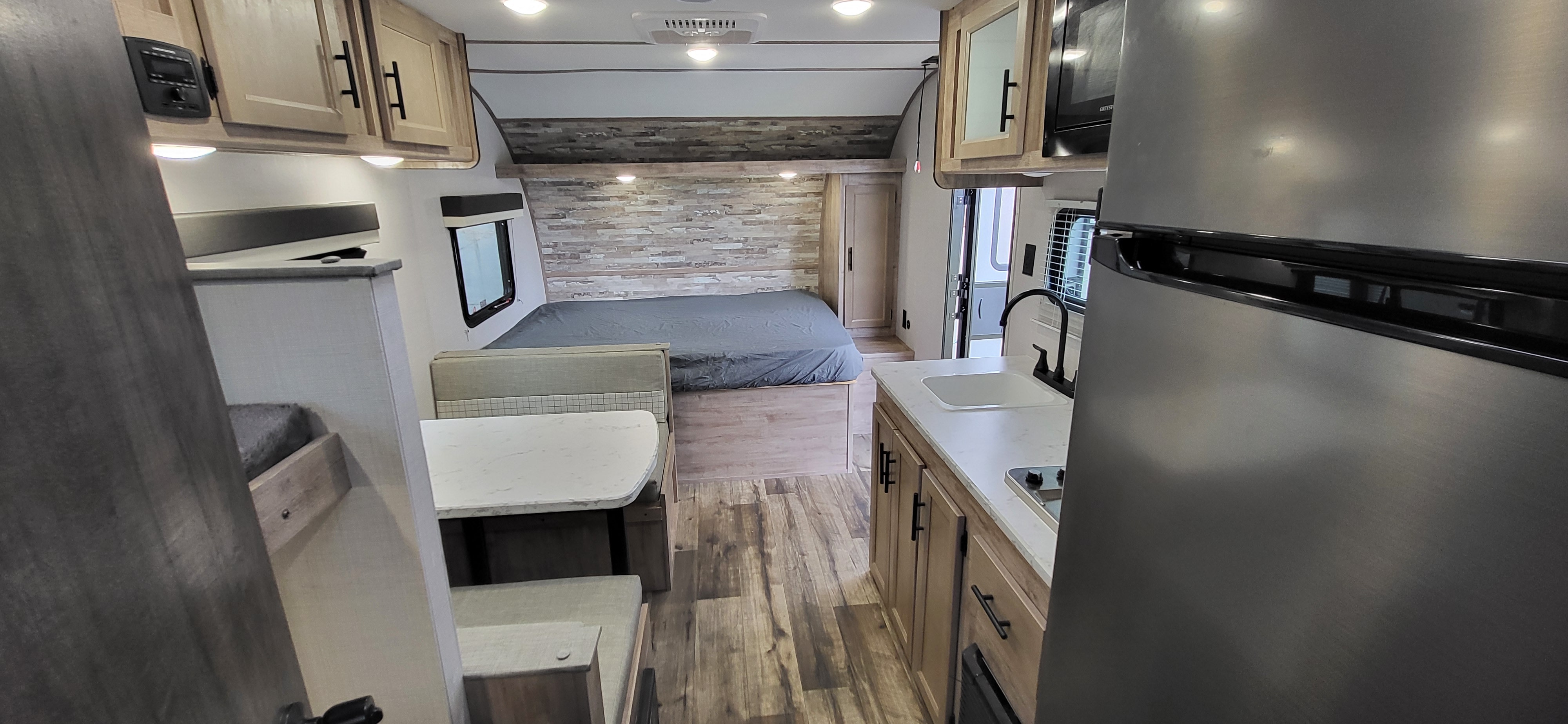 Step inside this modern RV rental: a compact interior featuring a full bed, dinette, and kitchen. Ideal for road trips.. Gulf Stream Ameri-Lite 2024