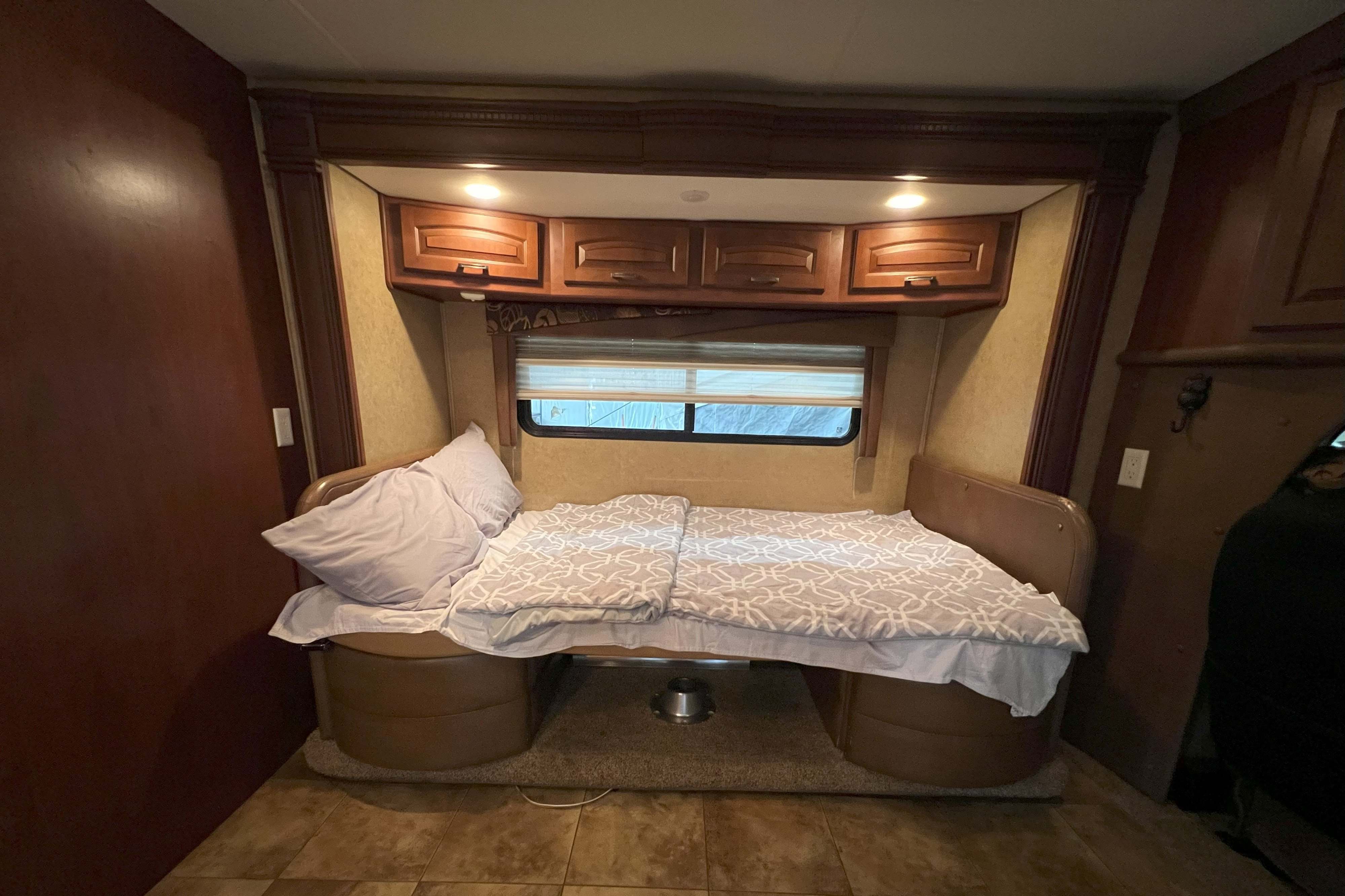 Cozy RV rental interior featuring a convertible bed/dinette, overhead cabinets, and window. Ideal for compact travel comfort.. Jayco Melbourne 2013