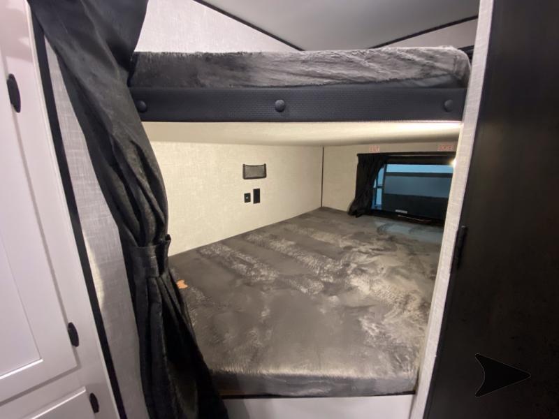 RV rental interior: cozy bunk beds with gray bedding, privacy curtain, and window for comfortable sleeping.. Bish 26BHS 2024