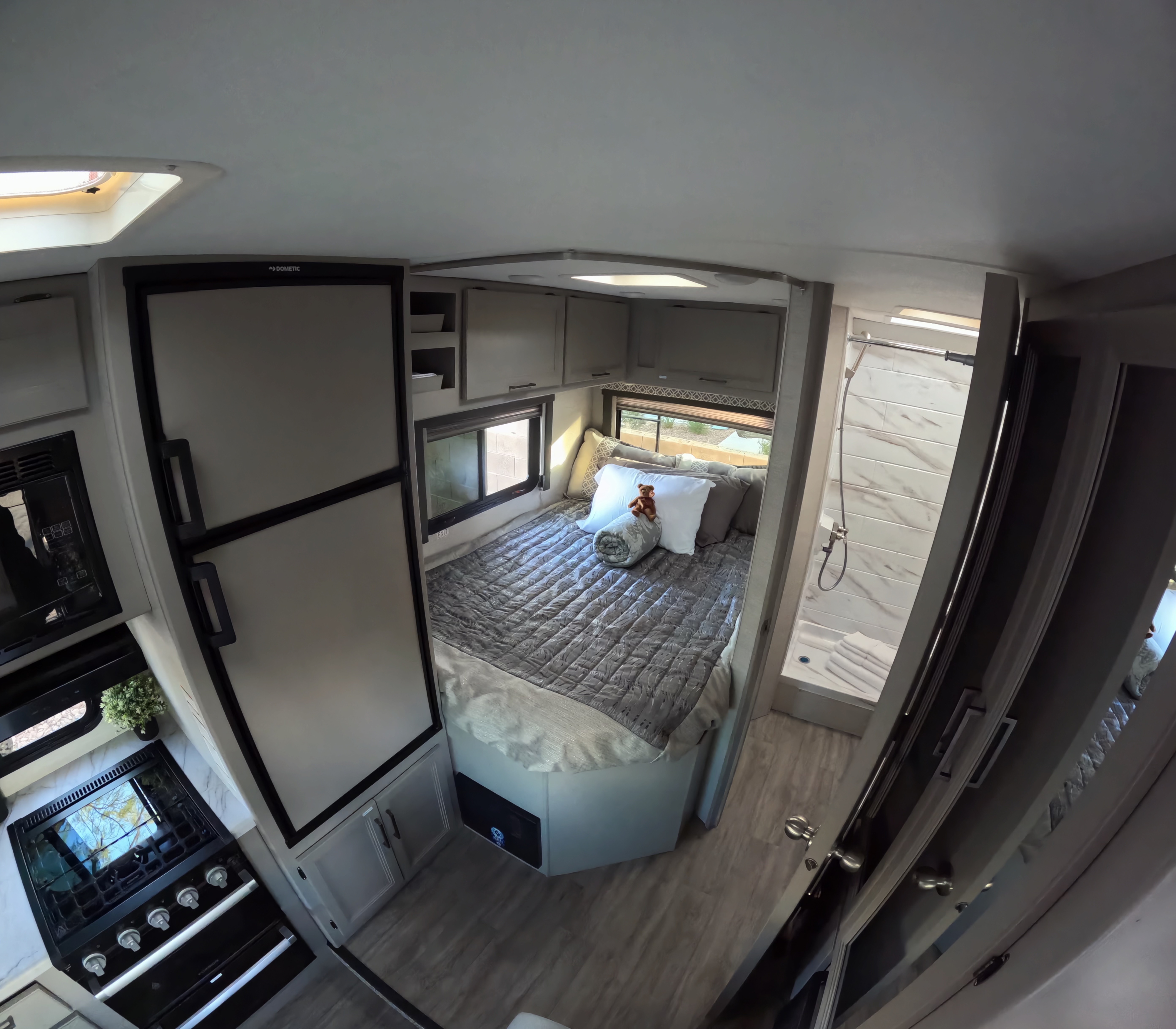 View inside a modern RV rental featuring a cozy bedroom, full kitchen with Dometic fridge, and a shower bathroom.. Thor Coleman 2024