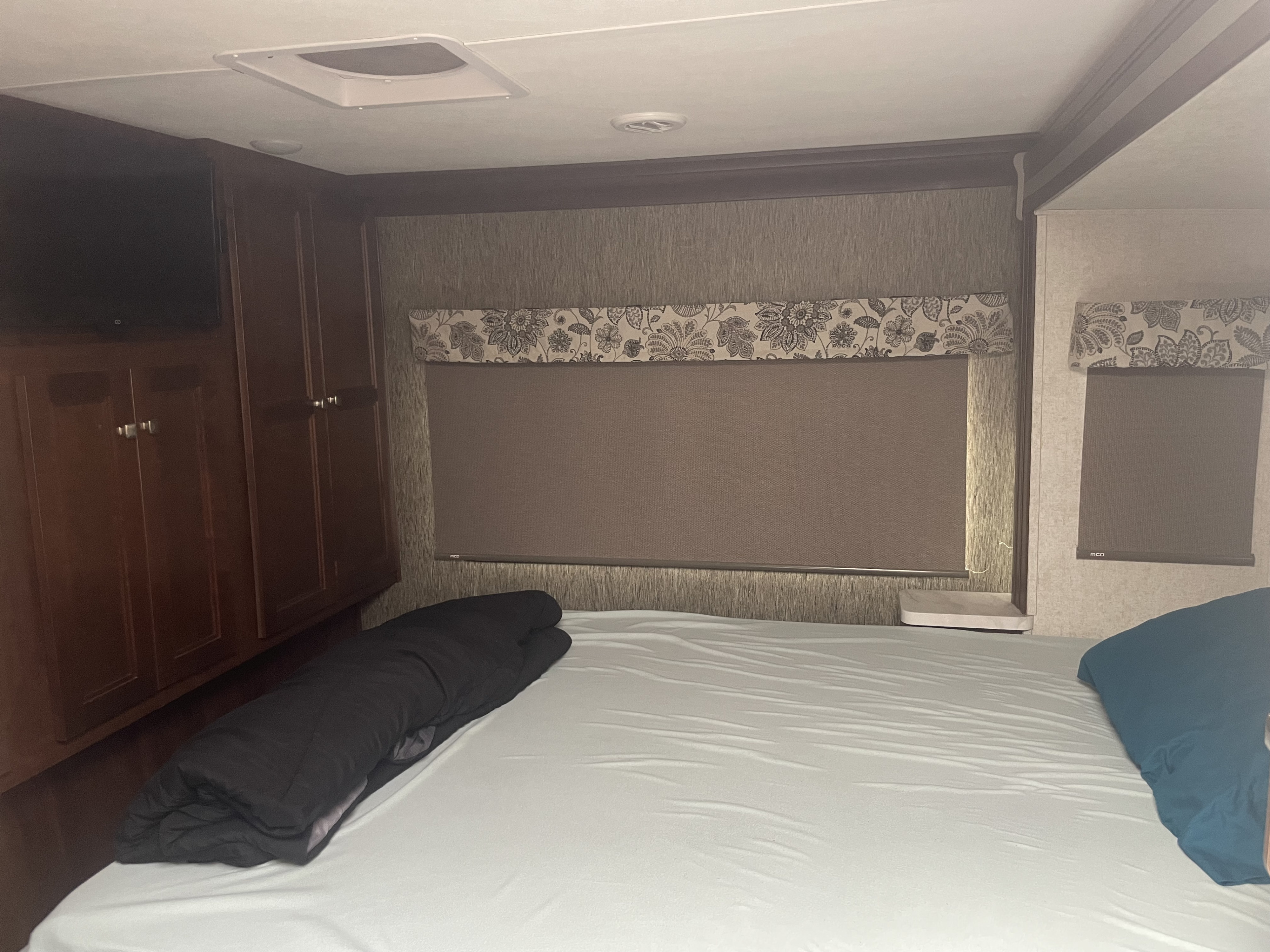 Cozy RV rental bedroom with dark wood cabinets, a comfy bed, and window shades, offering comfort on the go.. Forester Forester Motorhome 2019