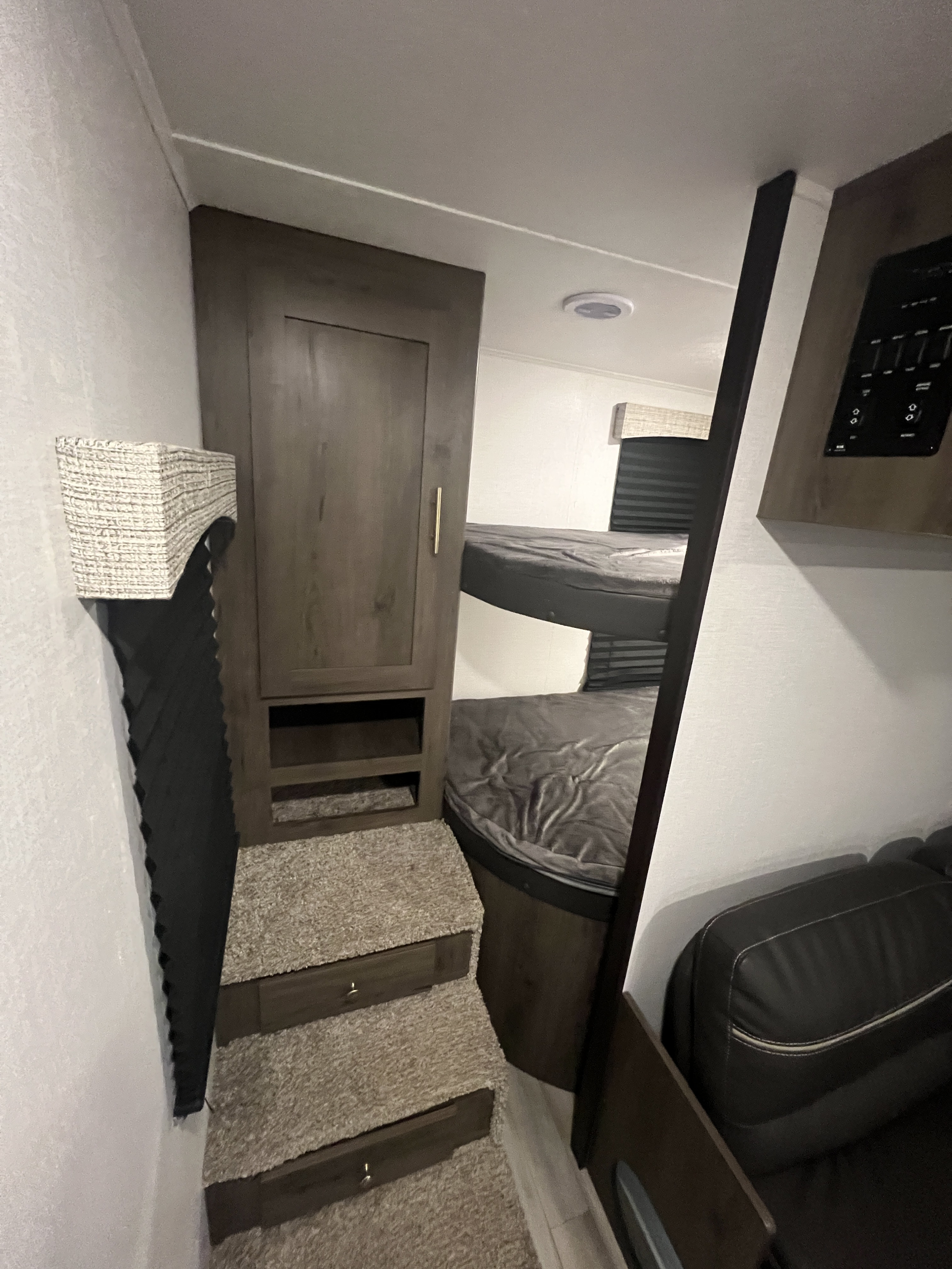 RV rental interior: bunk beds, carpeted steps with storage, and a sofa, plus wall controls.. Coachmen 262BHS 2022