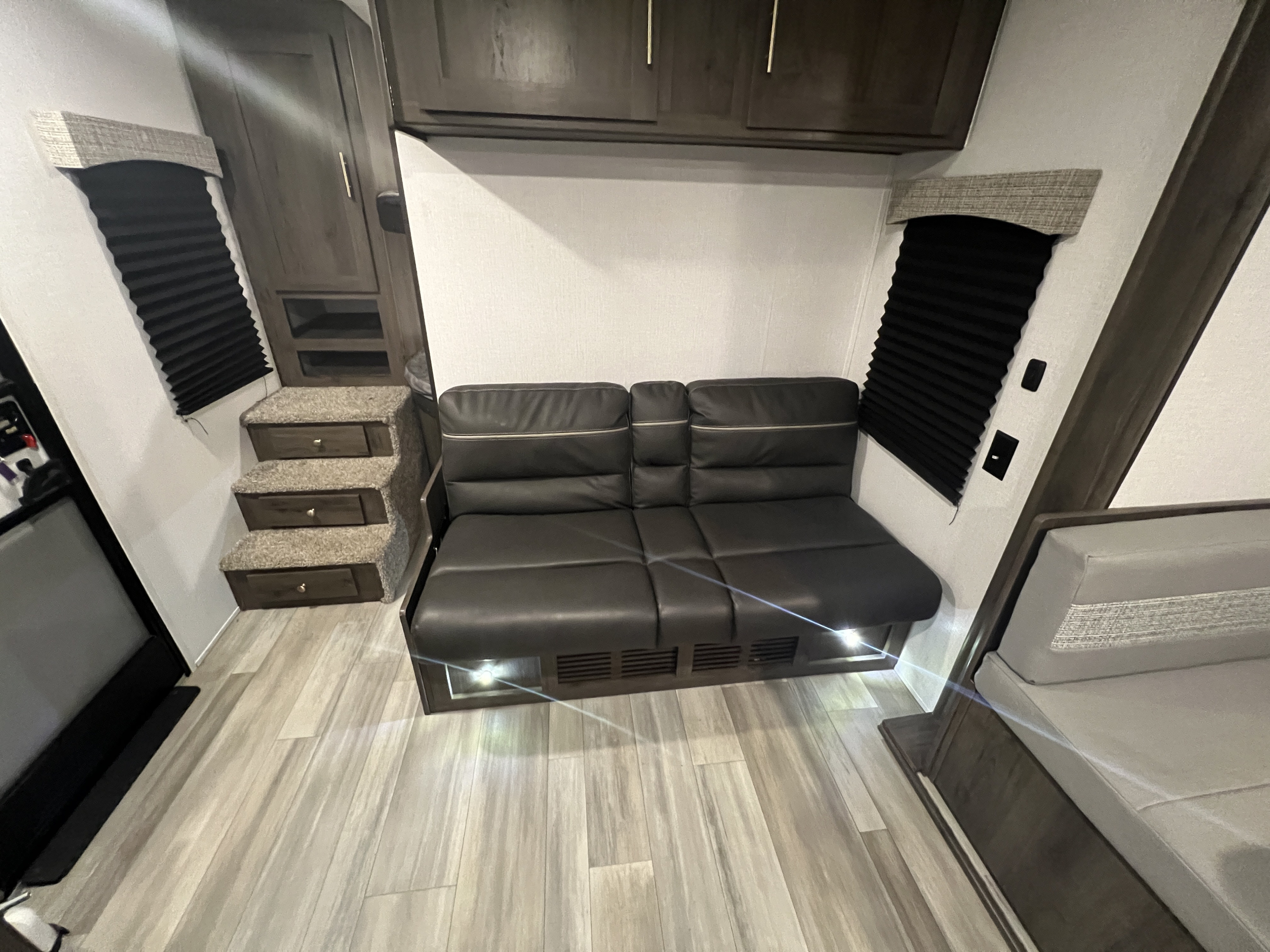 This RV rental offers a well-appointed interior: a dark sofa, wood-look flooring, built-in steps, and storage cabinetry.. Coachmen 262BHS 2022