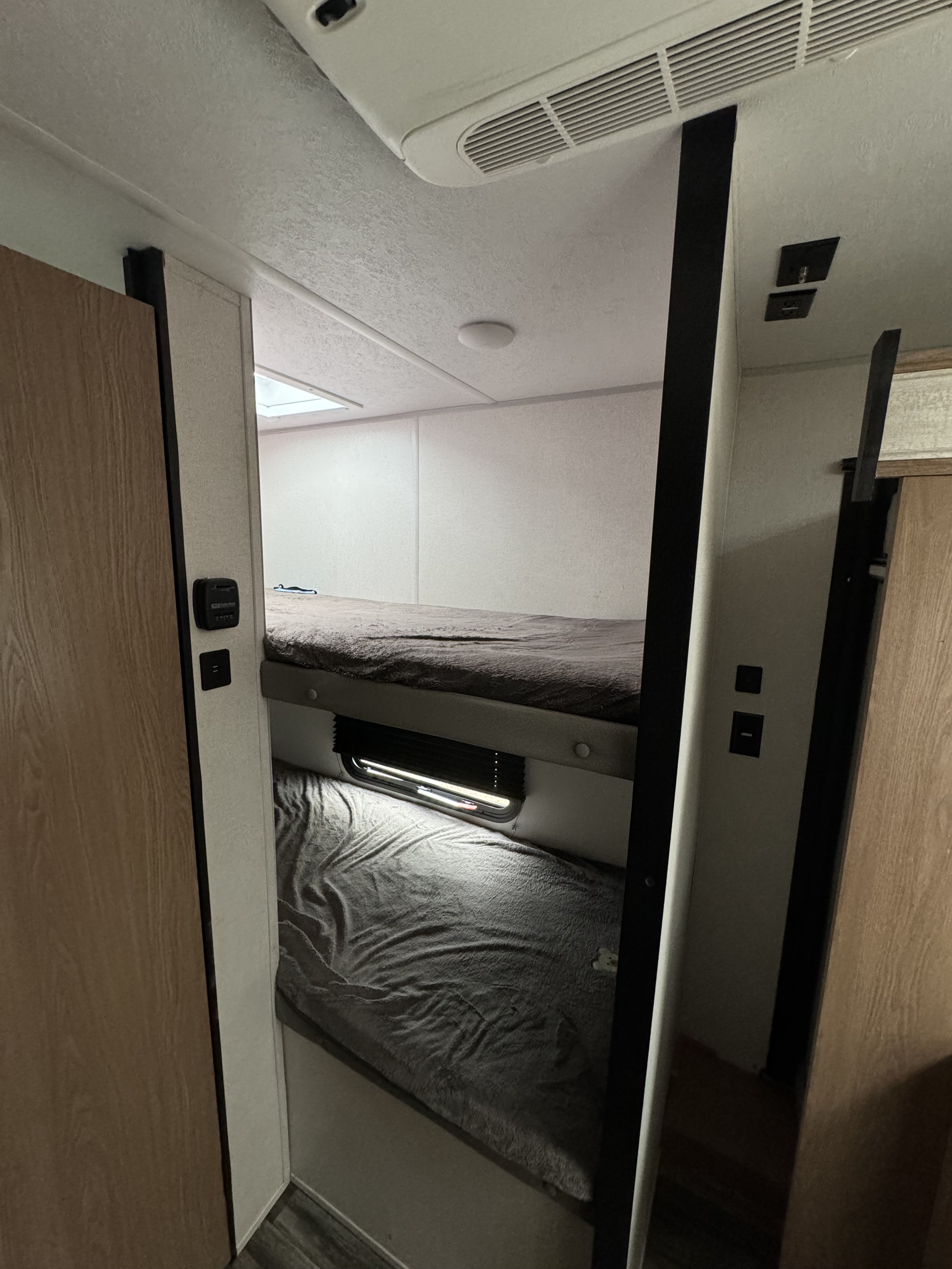 Experience comfort in this RV rental's cozy bunk beds with soft grey blankets. Ideal sleeping space for travel.. Forest River Primetime Avenger LT 2022