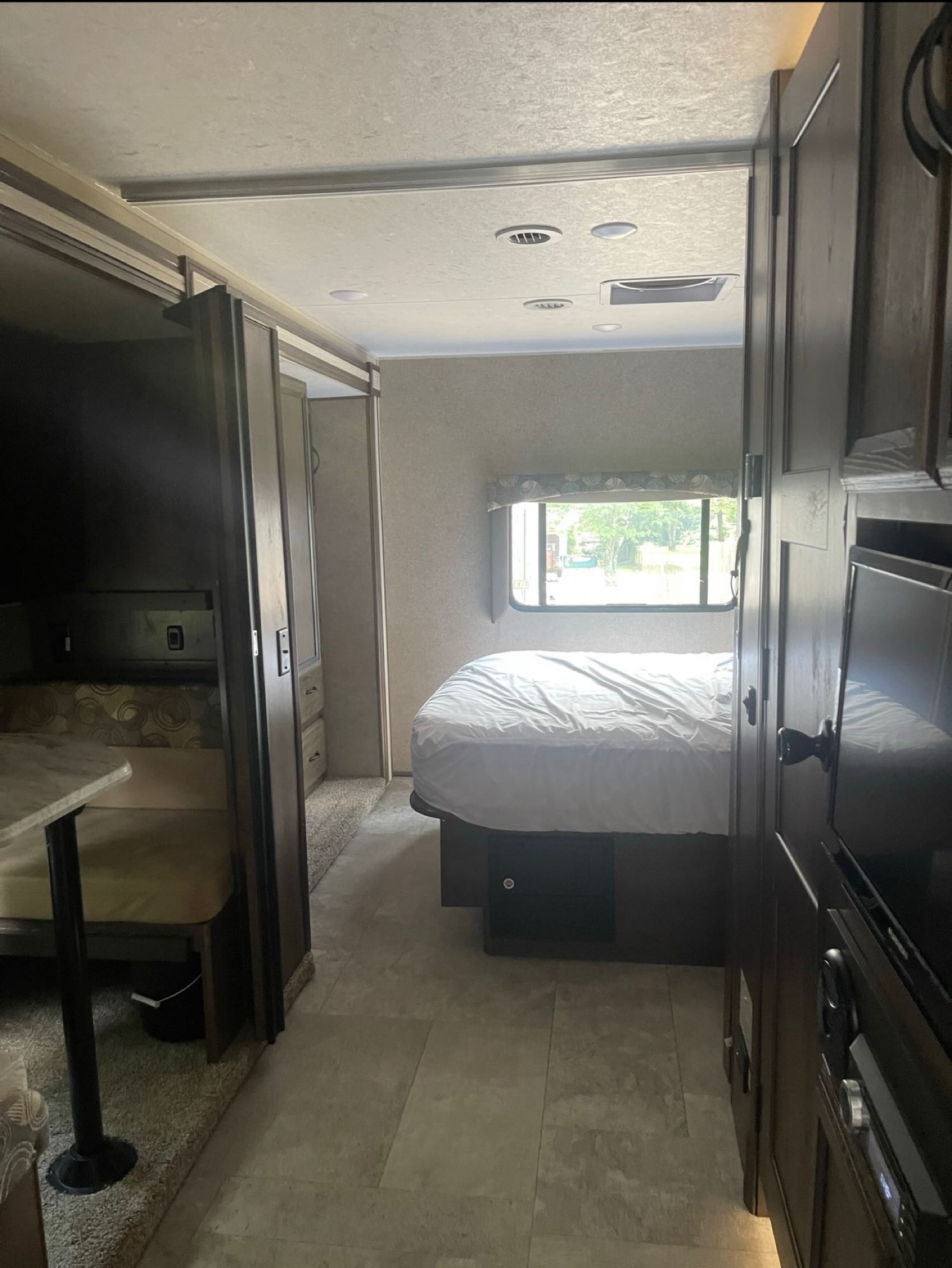 Experience comfort in this RV rental! View of the bedroom, complete with bed and window, and the dinette space. Dark wood interior.. Ford Coachman 2018