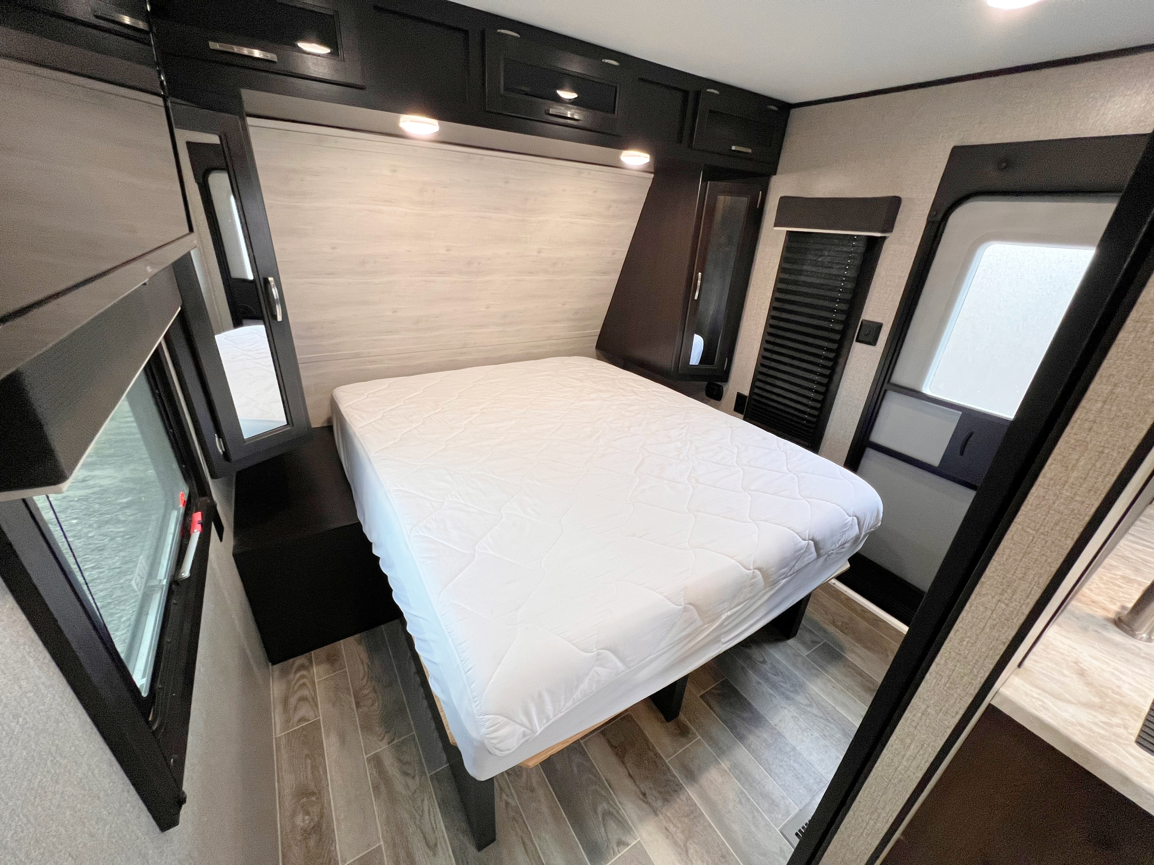 Modern RV rental bedroom with comfy queen bed, overhead cabinets, and window. Ideal for your next road trip.. Jayco Jayflight 2021