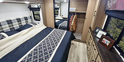 Relax in this cozy RV rental bedroom featuring a comfortable bed, dresser, closet, and scenic window views.. KZ Durango 2024