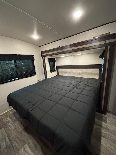 Comfortable RV rental bedroom featuring a large bed, overhead storage, and window with blinds.. Crossroads Sunset Trail Super Lite 2022