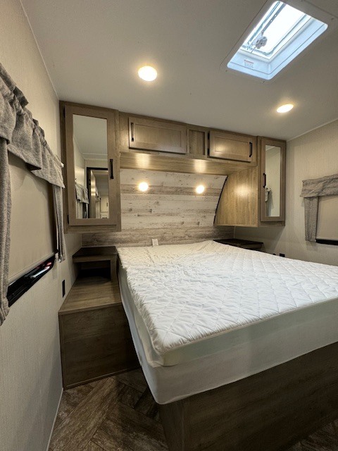 RV rental bedroom with a queen bed, built-in storage, and a skylight. Light walls, wood-look floor.. Palomino Puma 2023