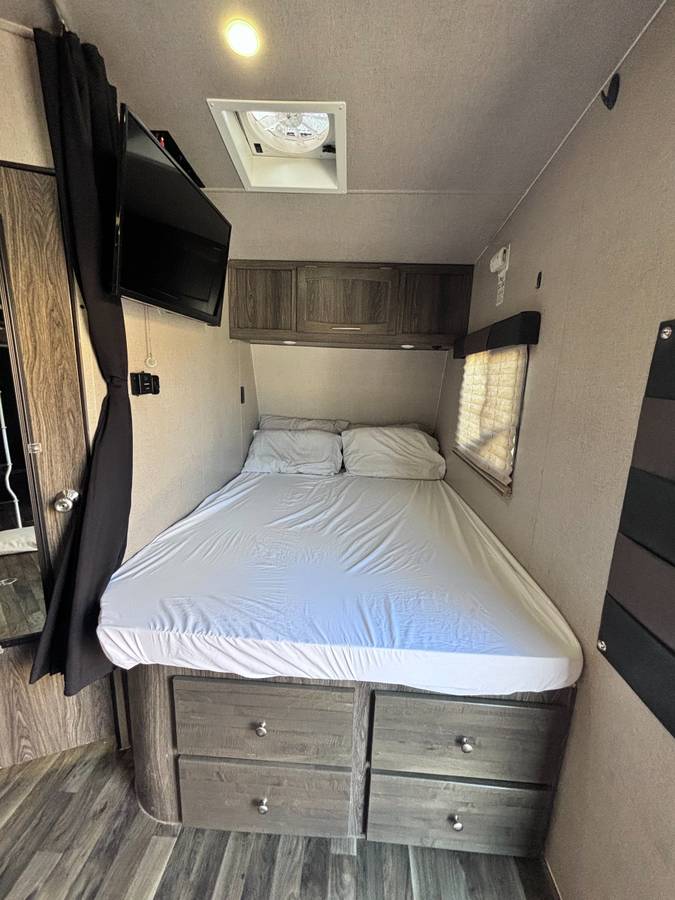 Inside this RV rental, find a compact bedroom with a comfy bed, drawers, TV, overhead storage, and ceiling vent.. Genesis Supreme Rv Genesis Supreme 2019