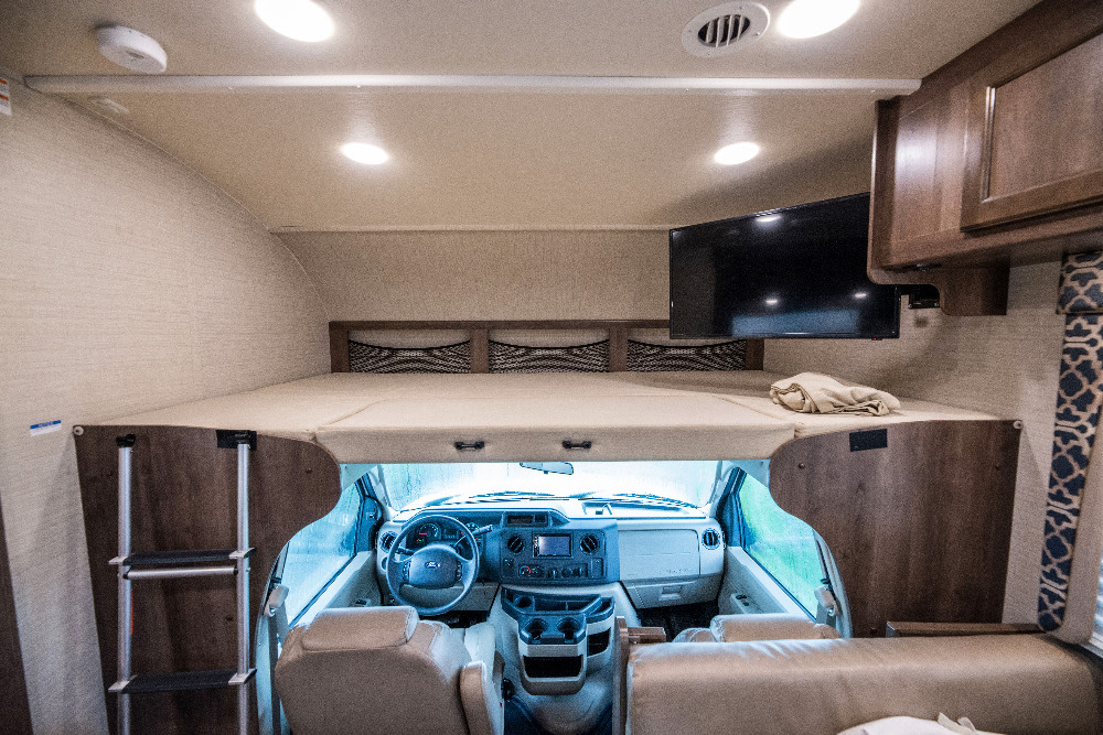 RV rental interior: a large overhead bunk bed over the driver's cabin, accessible by ladder, with a TV.. Jayco Redhawk 2018