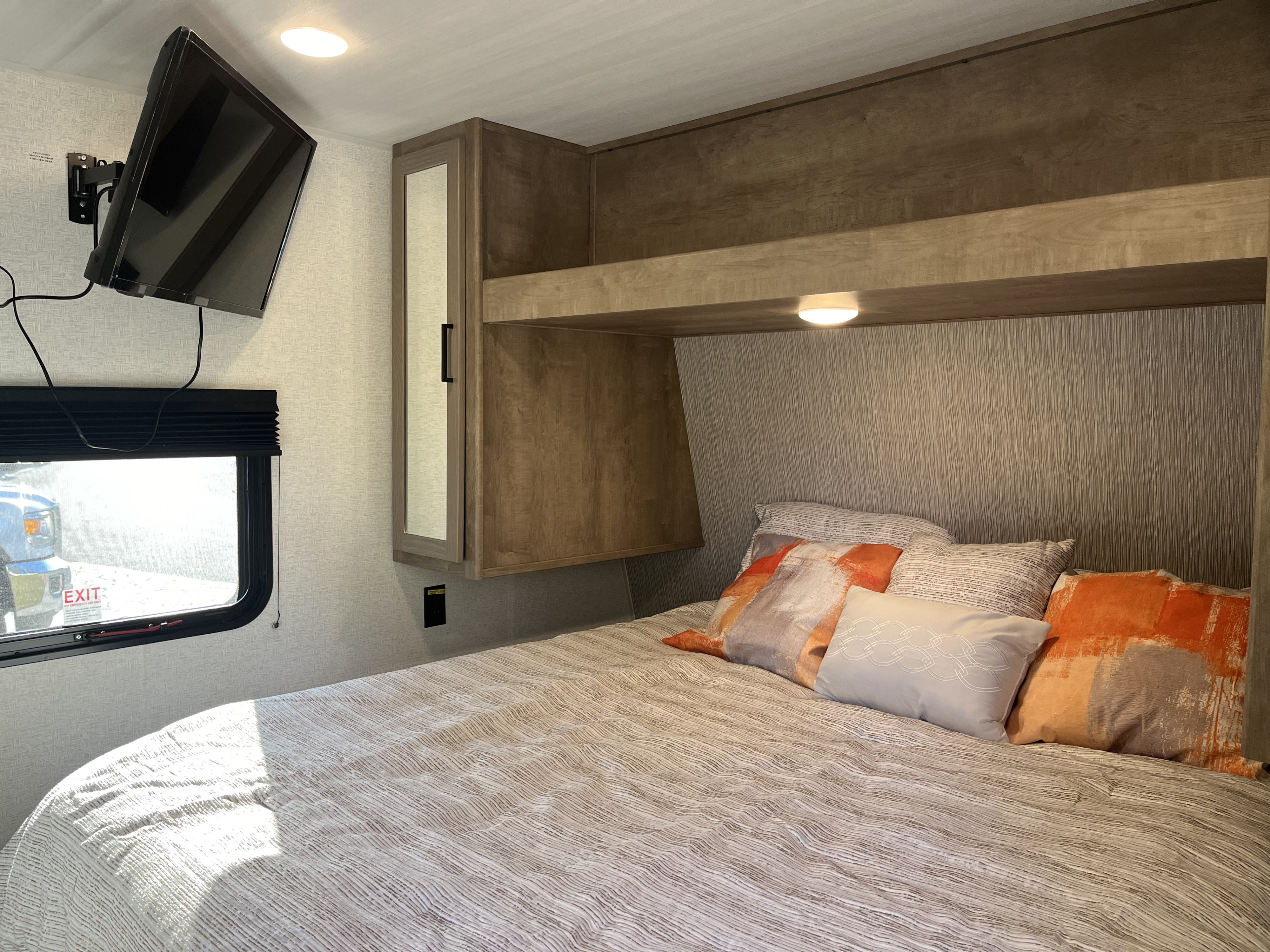 Cozy RV rental bedroom with TV, bed, storage cabinets, and natural light from the window.. Keystone Springdale 200RLC 2025