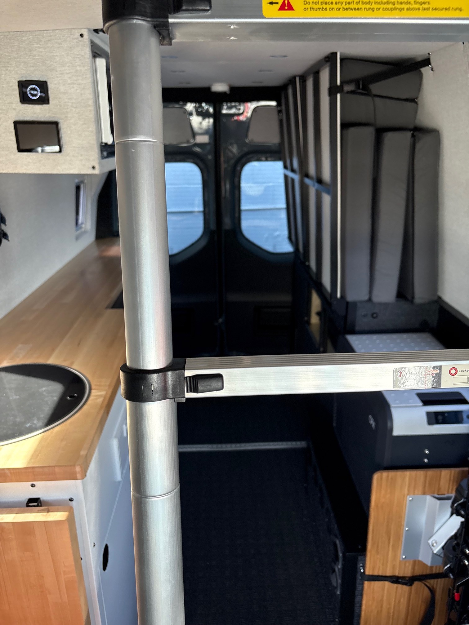 RV rental: View of van interior featuring a compact kitchen, portable fridge, versatile bed, and ladder.. Grit Overland Link 148 2025