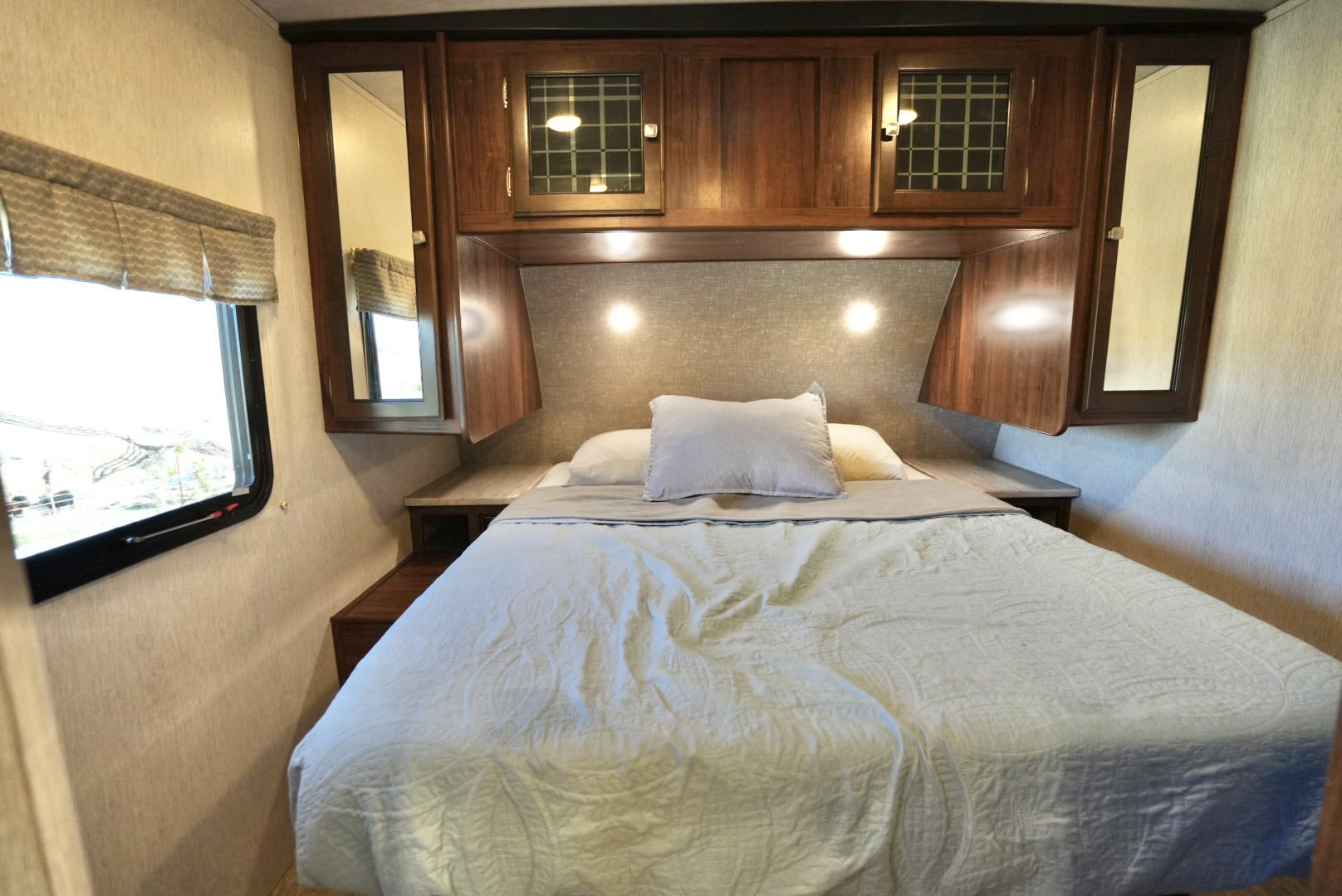 Spacious RV rental bedroom with comfy queen bed, overhead storage, and reading lights.. Heartland RVs Mallard 2019