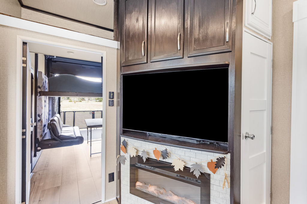 Inside this RV rental: modern living space with TV, electric fireplace, and a versatile toy hauler area with bunks.. Grand Design Momentum Toy Hauler 2018