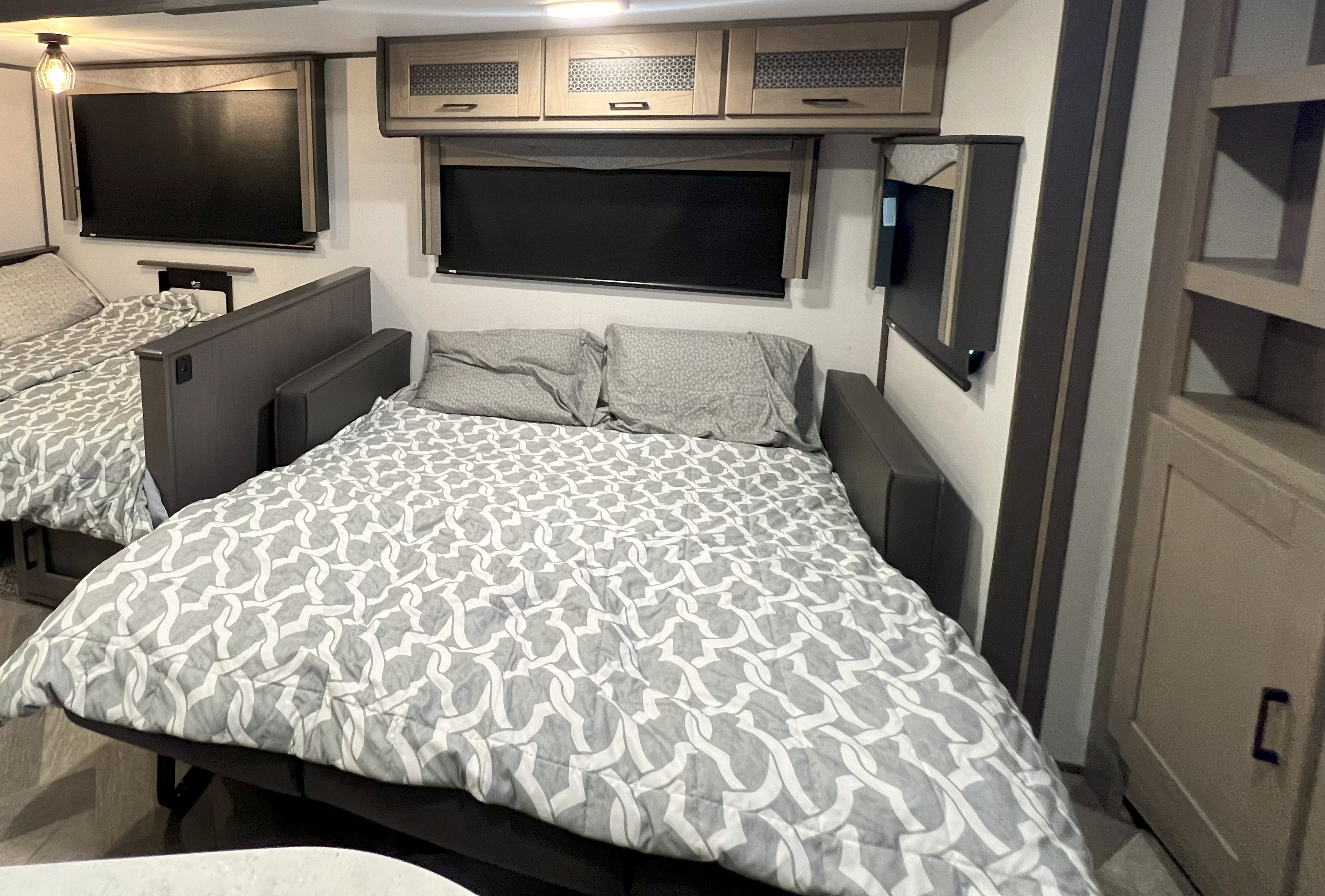 Comfortable RV rental sleeping area with two beds, gray & white patterned bedding, wall-mounted TVs, and overhead cabinets.. Twilight SIGNATURE TWS 3300 2021