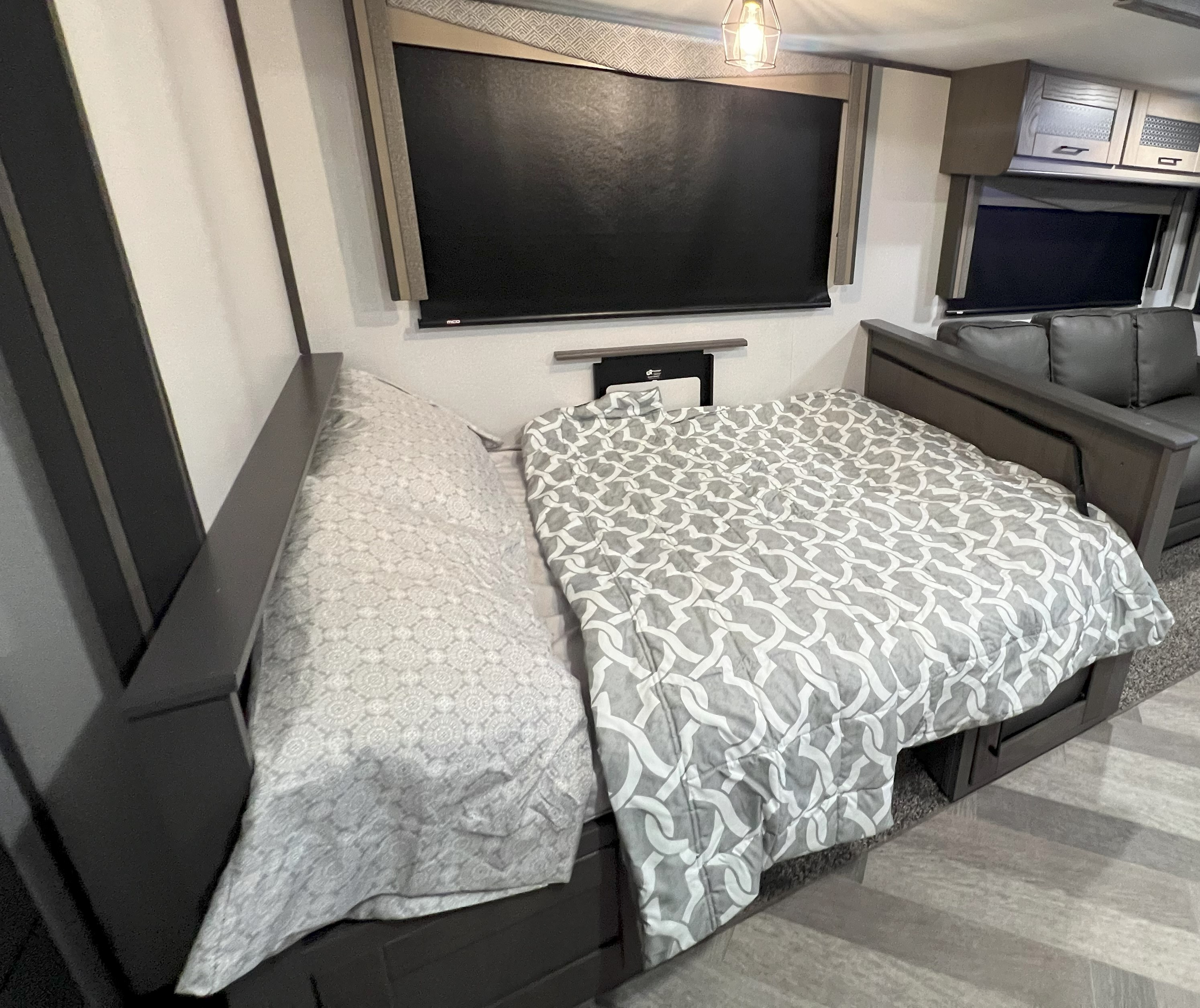 Cozy RV rental interior with a comfy pull-down Murphy bed, patterned bedding, wall screen, and living space.. Twilight SIGNATURE TWS 3300 2021
