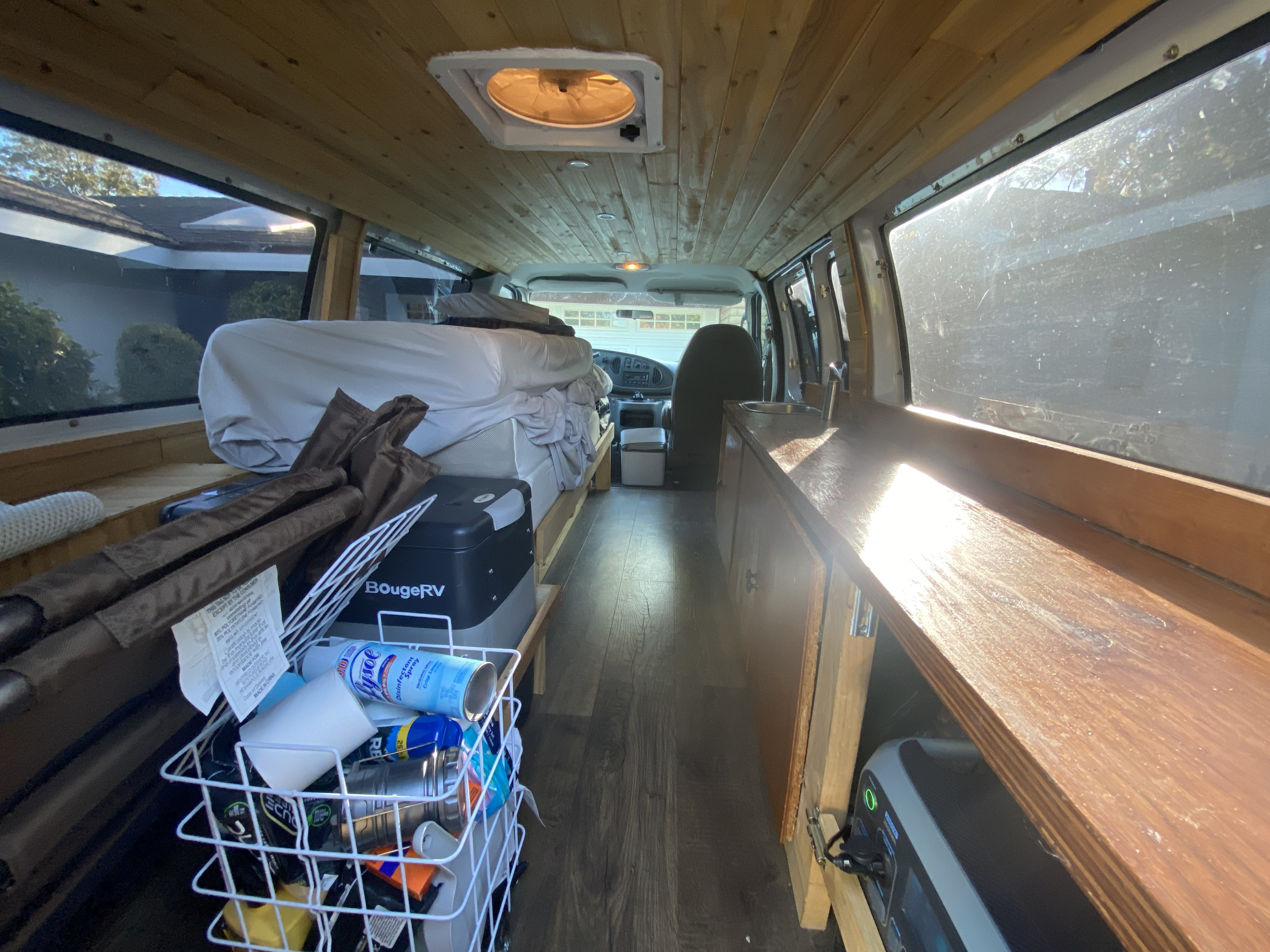Explore this rv rental camper van's interior: wood-paneled, with a cozy bed, sink area, and organized storage.. Ford Econoline 150 2003