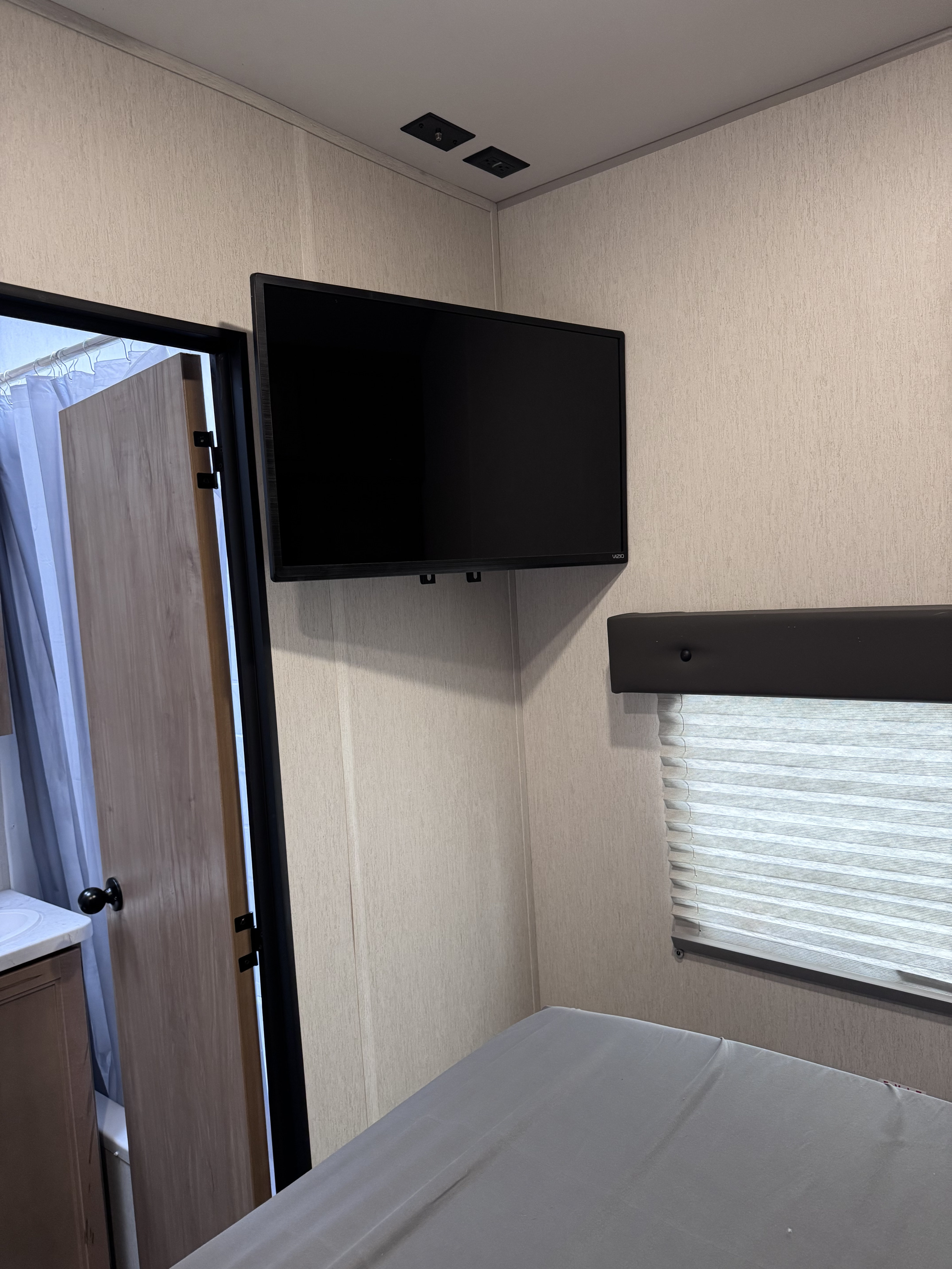 Cozy RV rental bedroom with TV, window, and bathroom entrance. Perfect for your next road trip.. Forest River Vengeance 2024