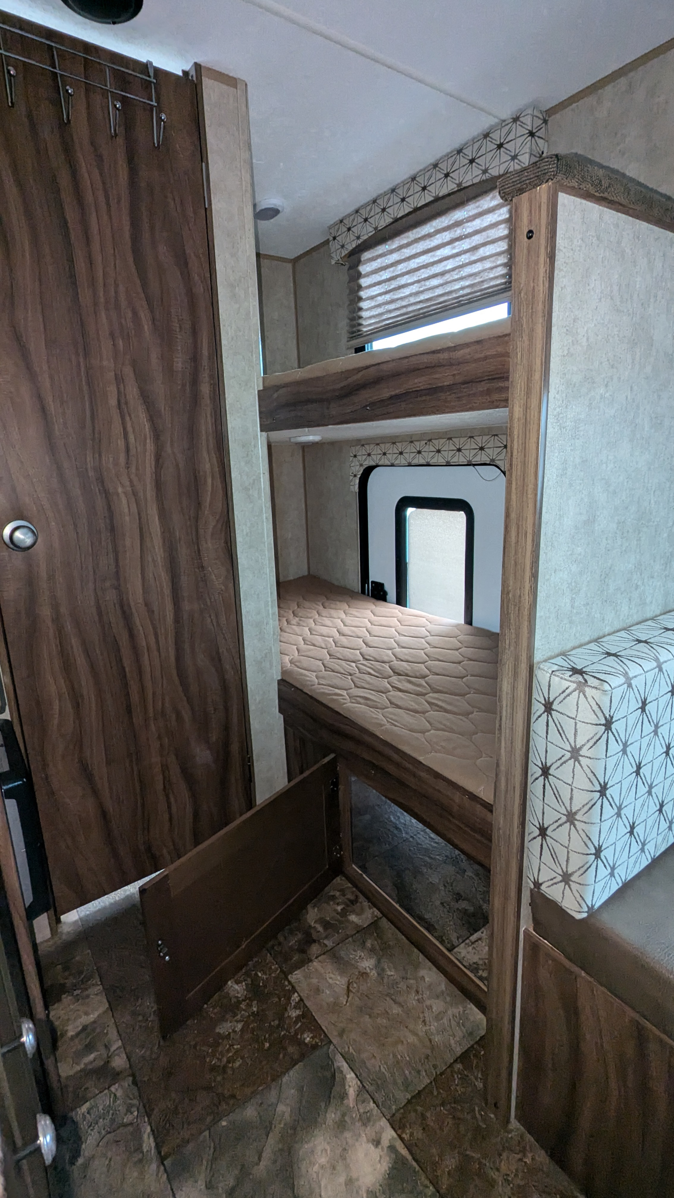 RV rental interior: cozy bunk beds with mattress, window, and accessible under-bunk storage in a camper.. Coachmen Viking 2017