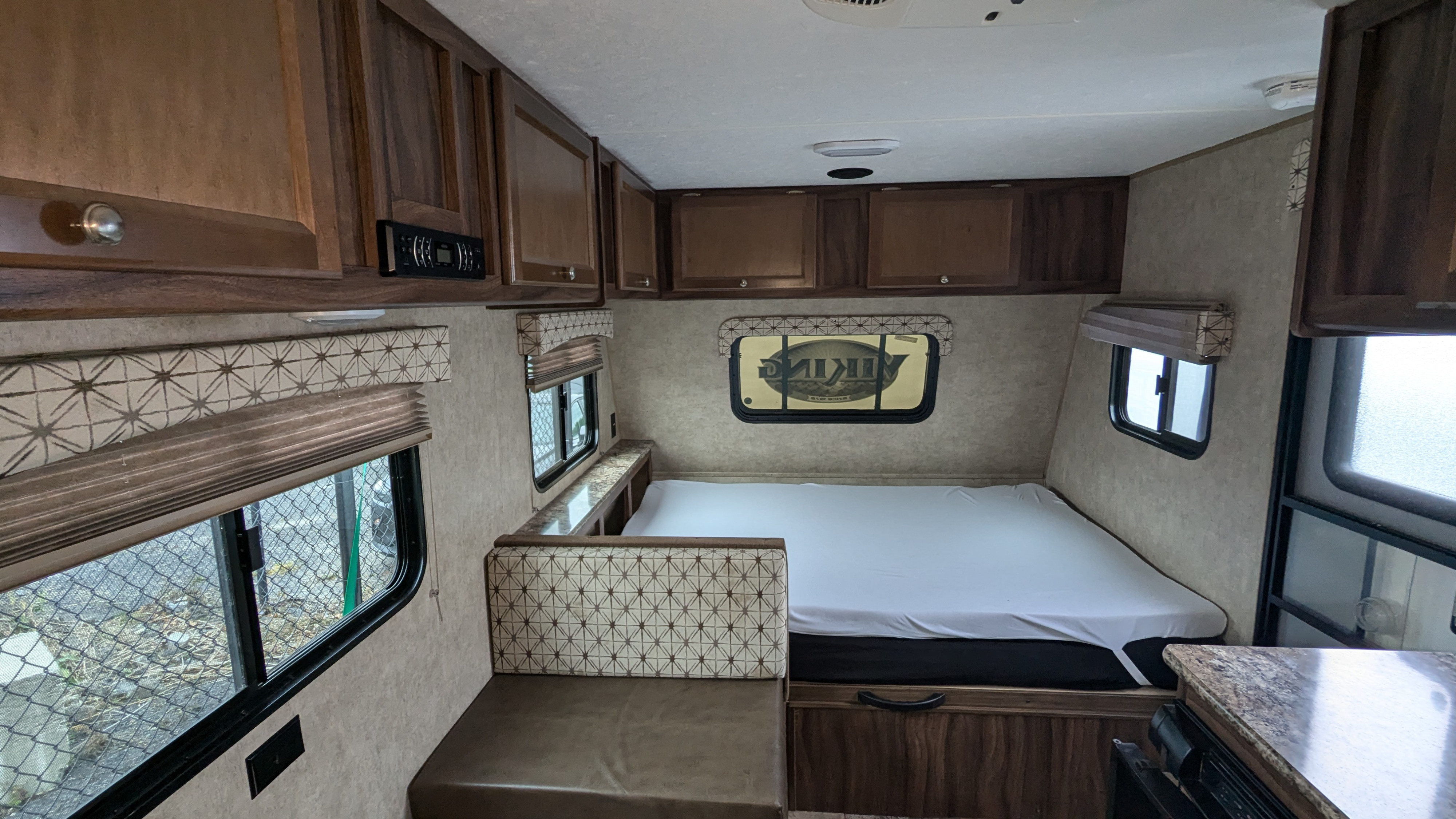 Explore this RV rental's interior: comfy bed, dinette seating, and ample wood cabinets for storage.. Coachmen Viking 2017
