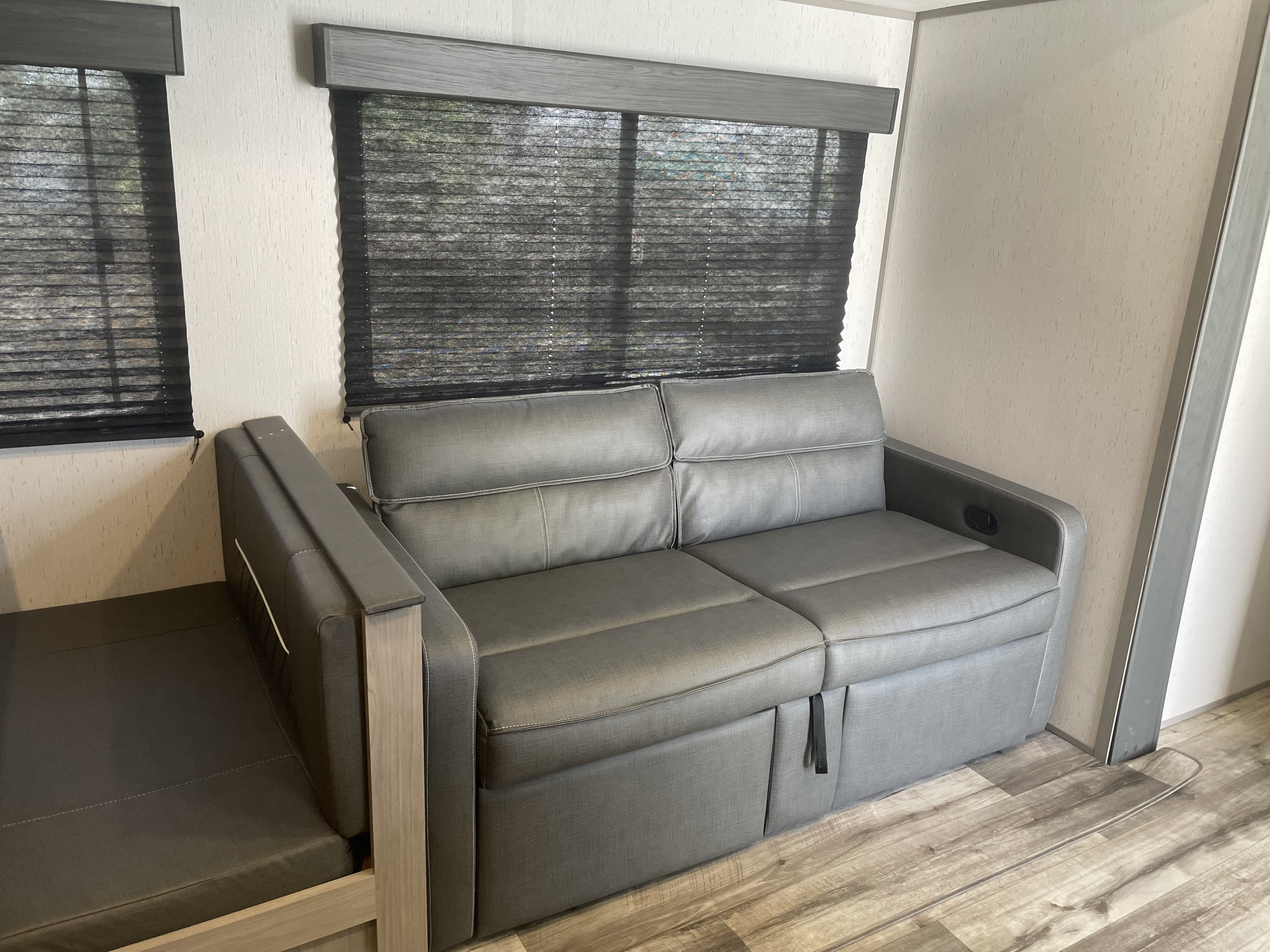 Modern rv rental: gray sofa-bed, dark pleated blinds, and wood-look flooring. A comfortable living space inside.. Dutchmen Coleman Lantern LT 2023