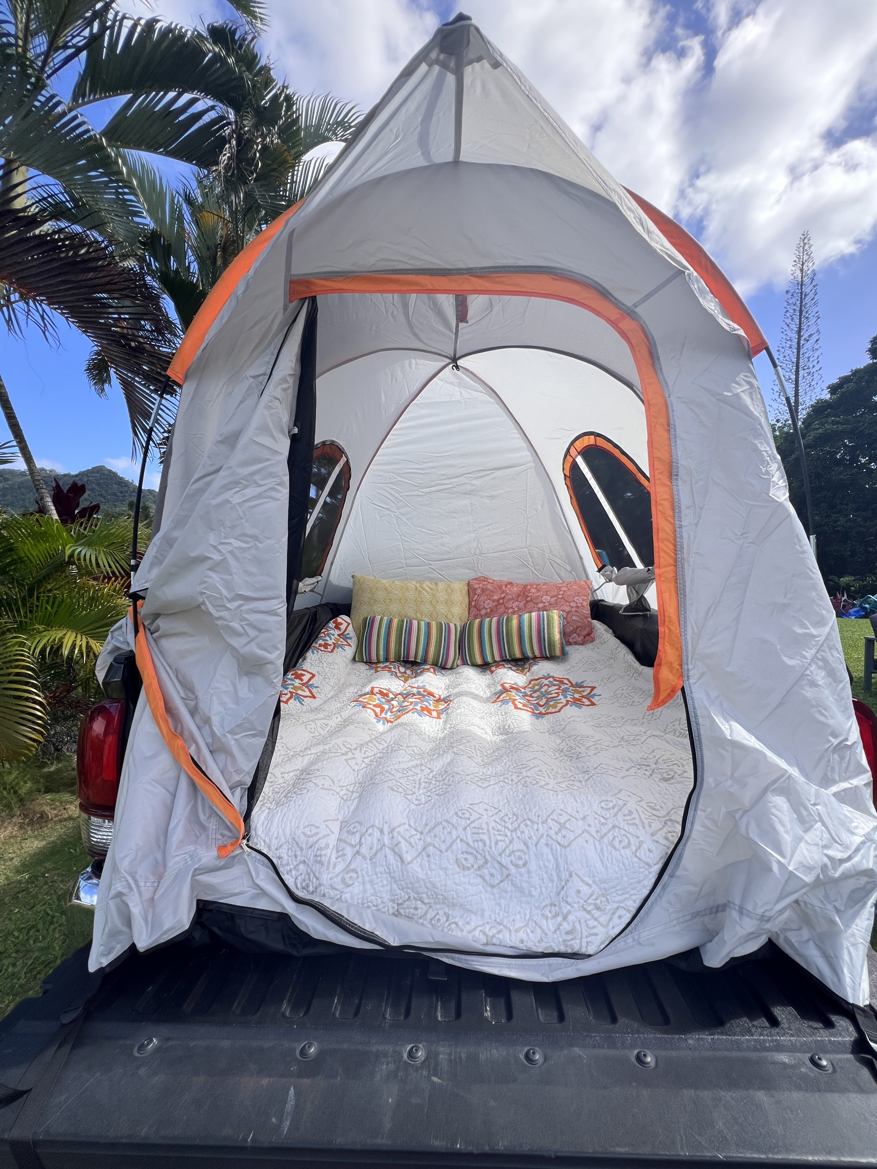 A cozy truck bed tent, an RV rental-like setup for camping adventures. White quilt, colorful pillows inside.. Xplorer Toyota Tacoma SR5 2018