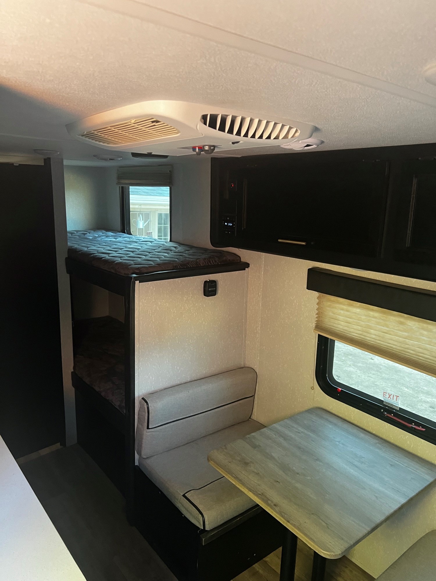 Inside an RV rental: bunk beds, dinette table with seating, window, and ceiling AC. Cozy interior for your trip.. Forest River Cherokee Wolf Pup Black Label 2021