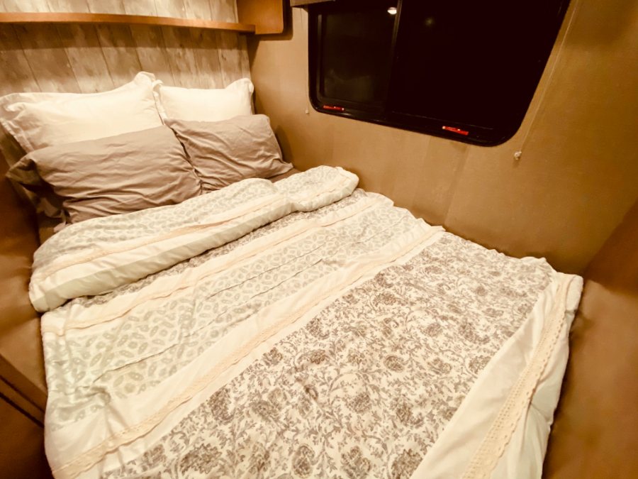 Inviting RV rental bed with plush pillows and a patterned comforter, offering comfort for your next adventure.. Winnebago 25 2019