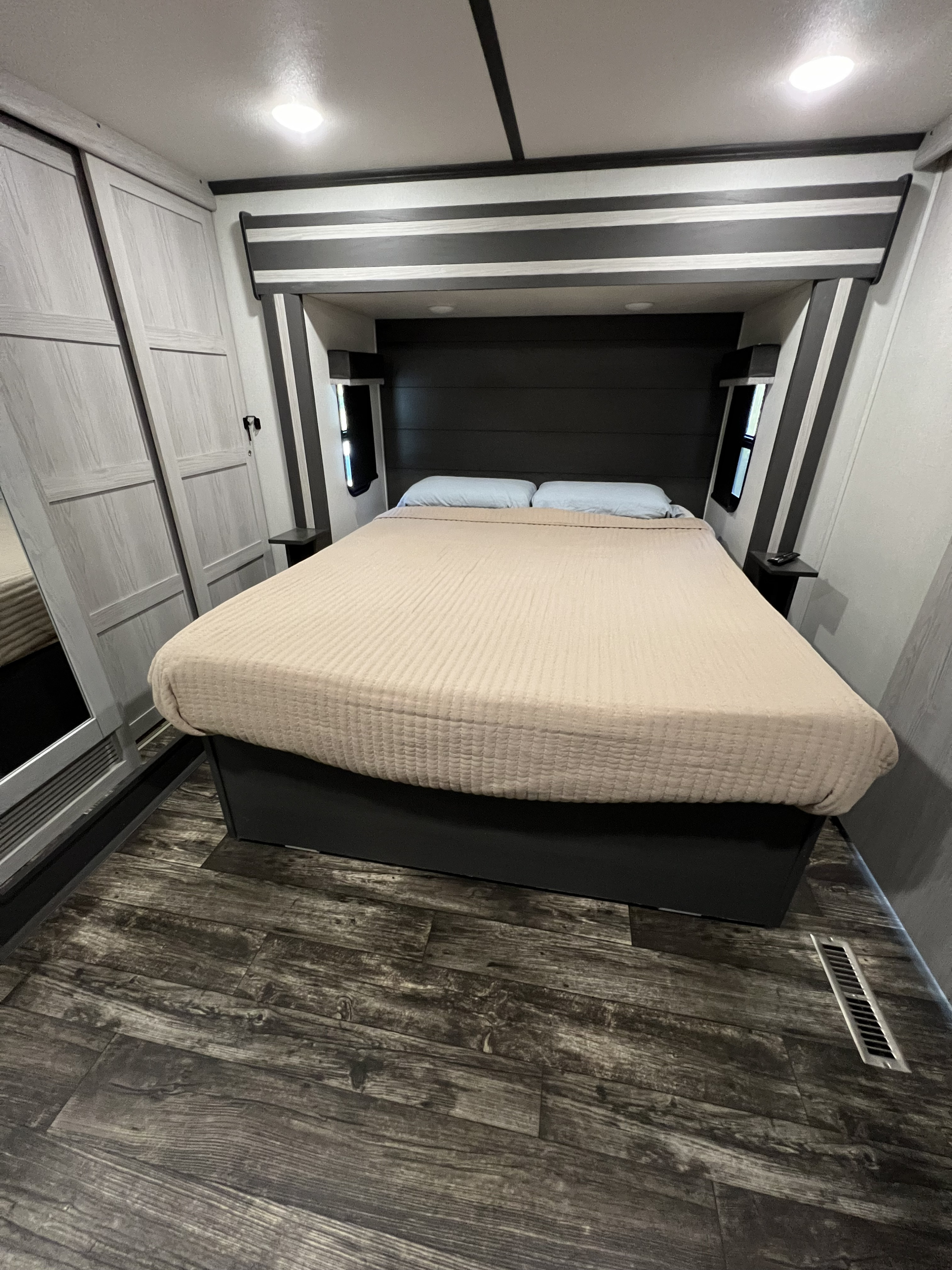 RV rental interior: A cozy bedroom with a large bed, built-in closet, and wood-look floor.. Keystone RV Fuzion Toy Hauler 2021