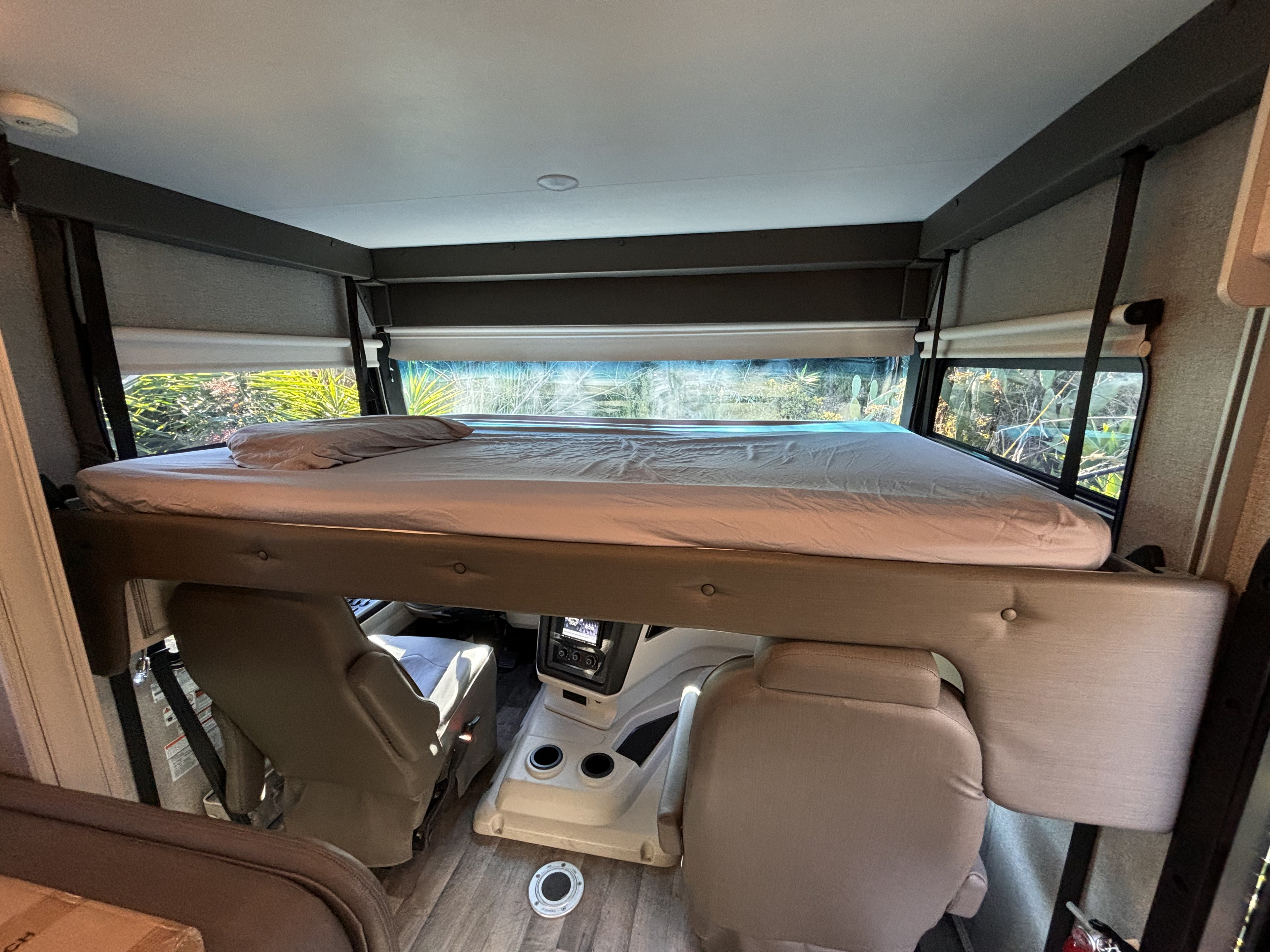 RV rental interior: A comfortable bunk bed positioned above the front seats and dashboard, offering window views.. Jayco Alante 2021