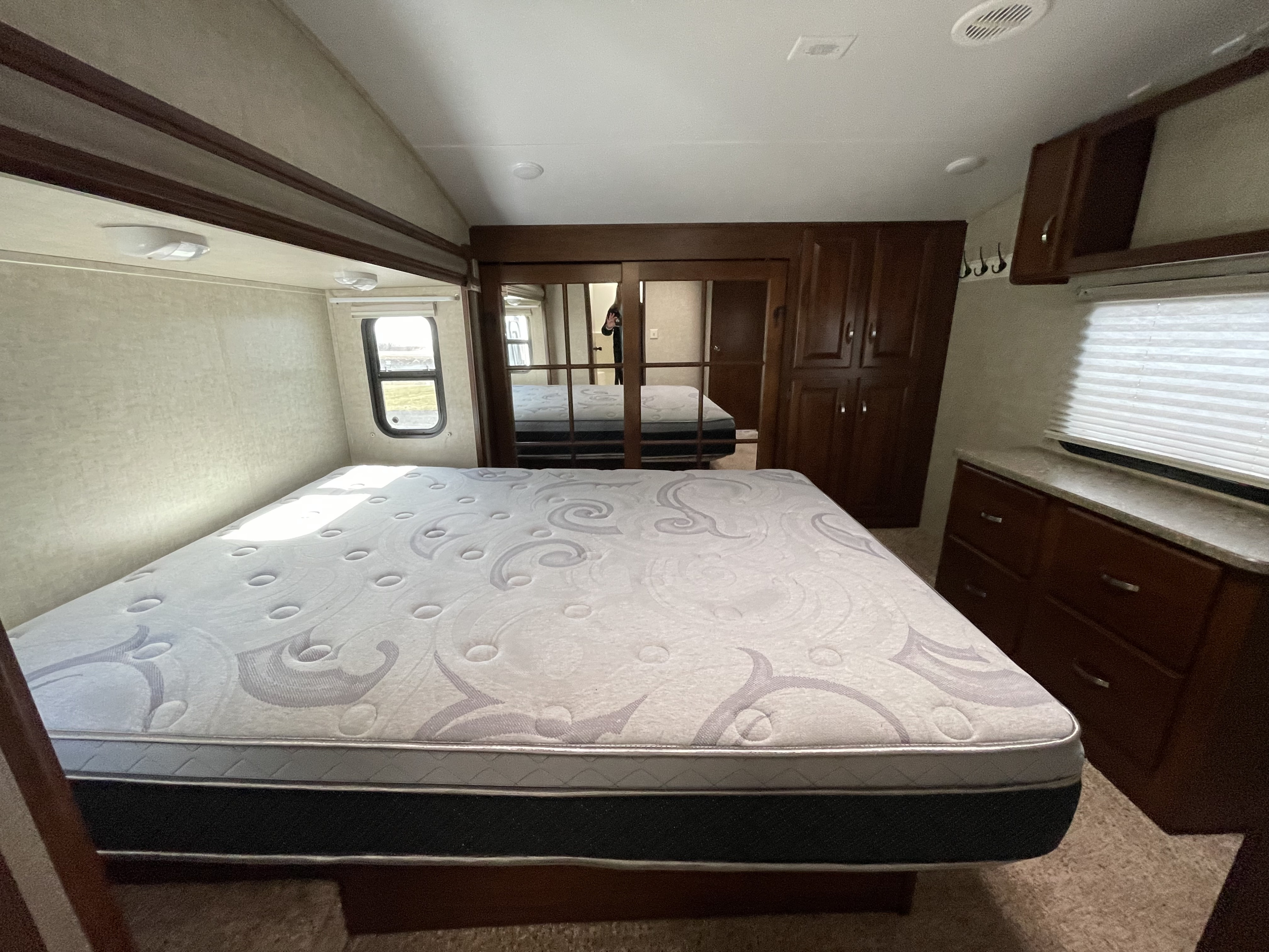 Spacious RV bedroom interior with a comfortable mattress and mirrored closet, ideal for your RV rental getaway.. Keystone Laredo 2013