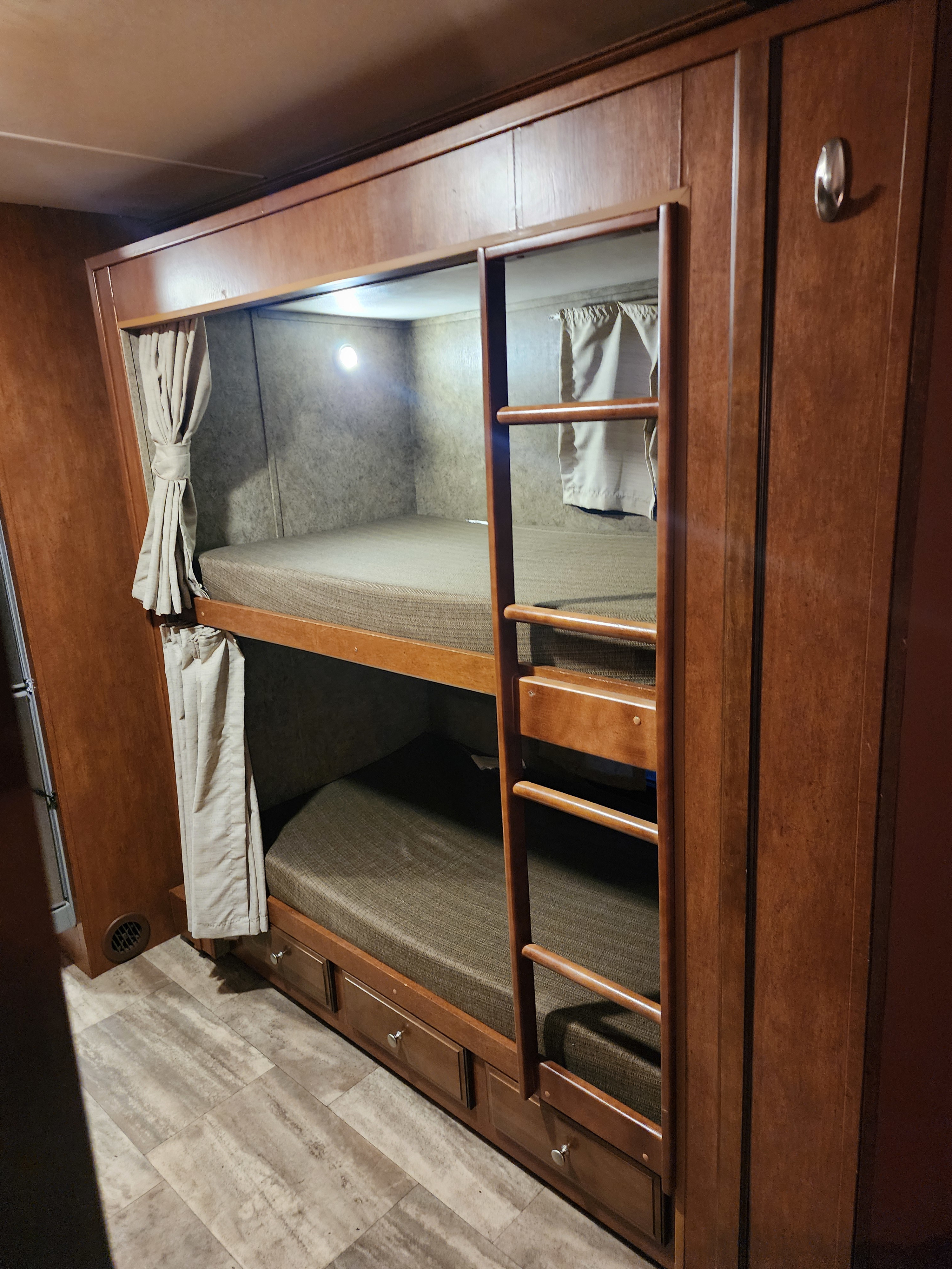 An RV rental's clever bunk bed setup: two sleeping areas with privacy curtains, built-in lights, and under-bed storage.. Forest River Georgetown 2015