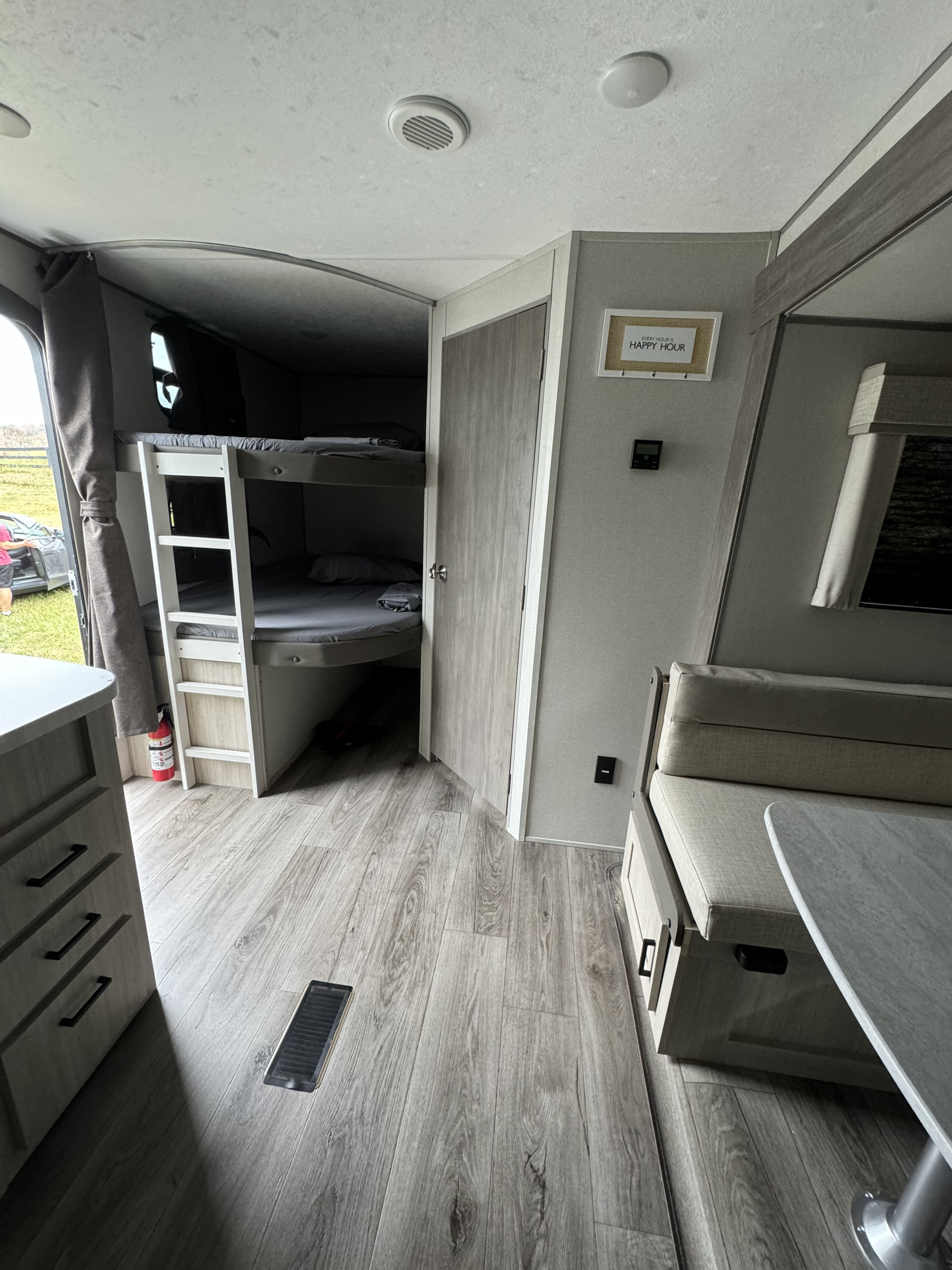 Cozy RV rental interior featuring bunk beds, a dining area, and modern wood-look flooring. Ideal for family adventures.. Coachmen Catalina legacy edition 2024