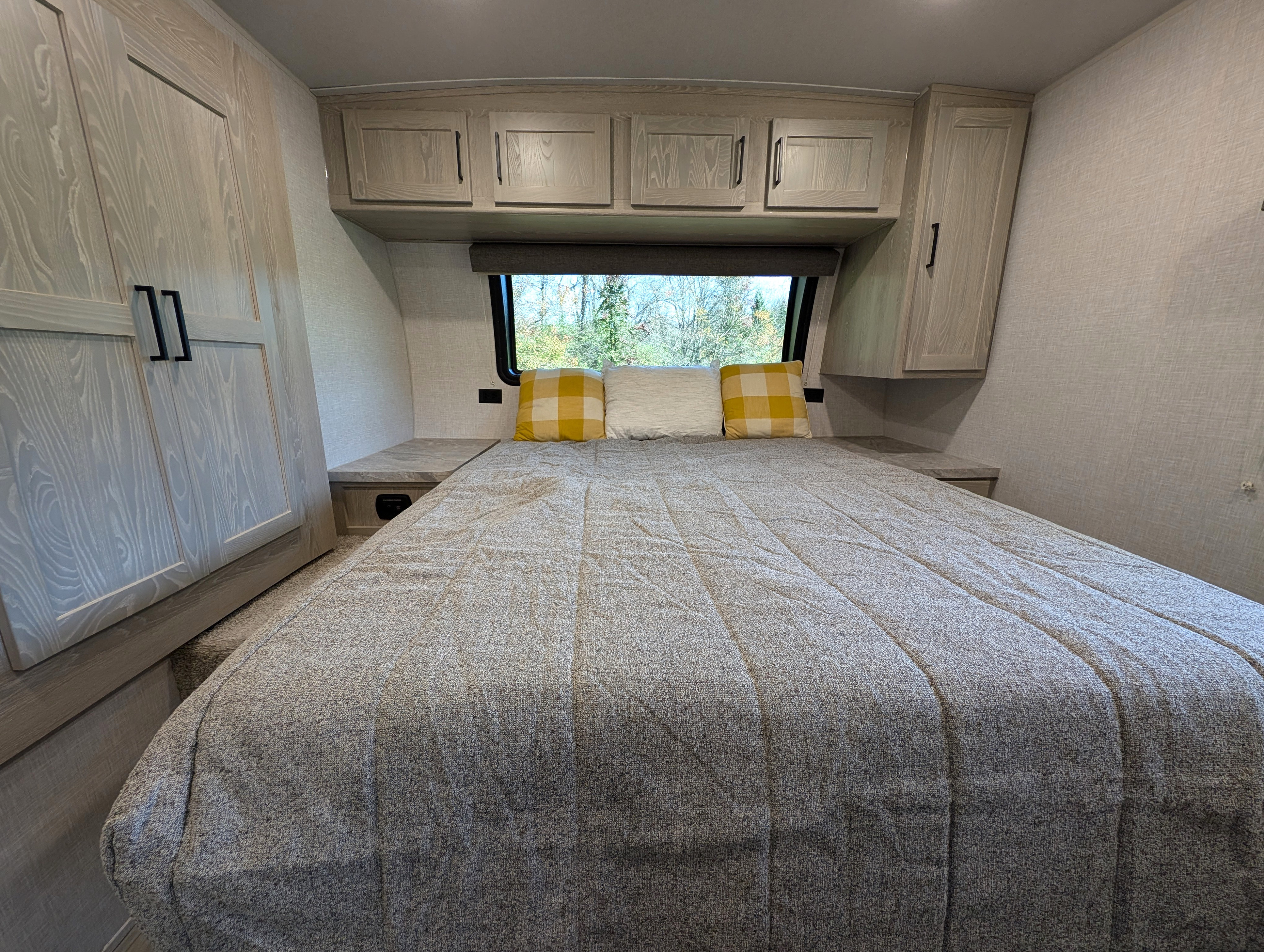 RV rental bedroom: a cozy retreat with comfy bed, light wood cabinets, and window overlooking trees.. Forest River Flagstaff Micro Lite 2021