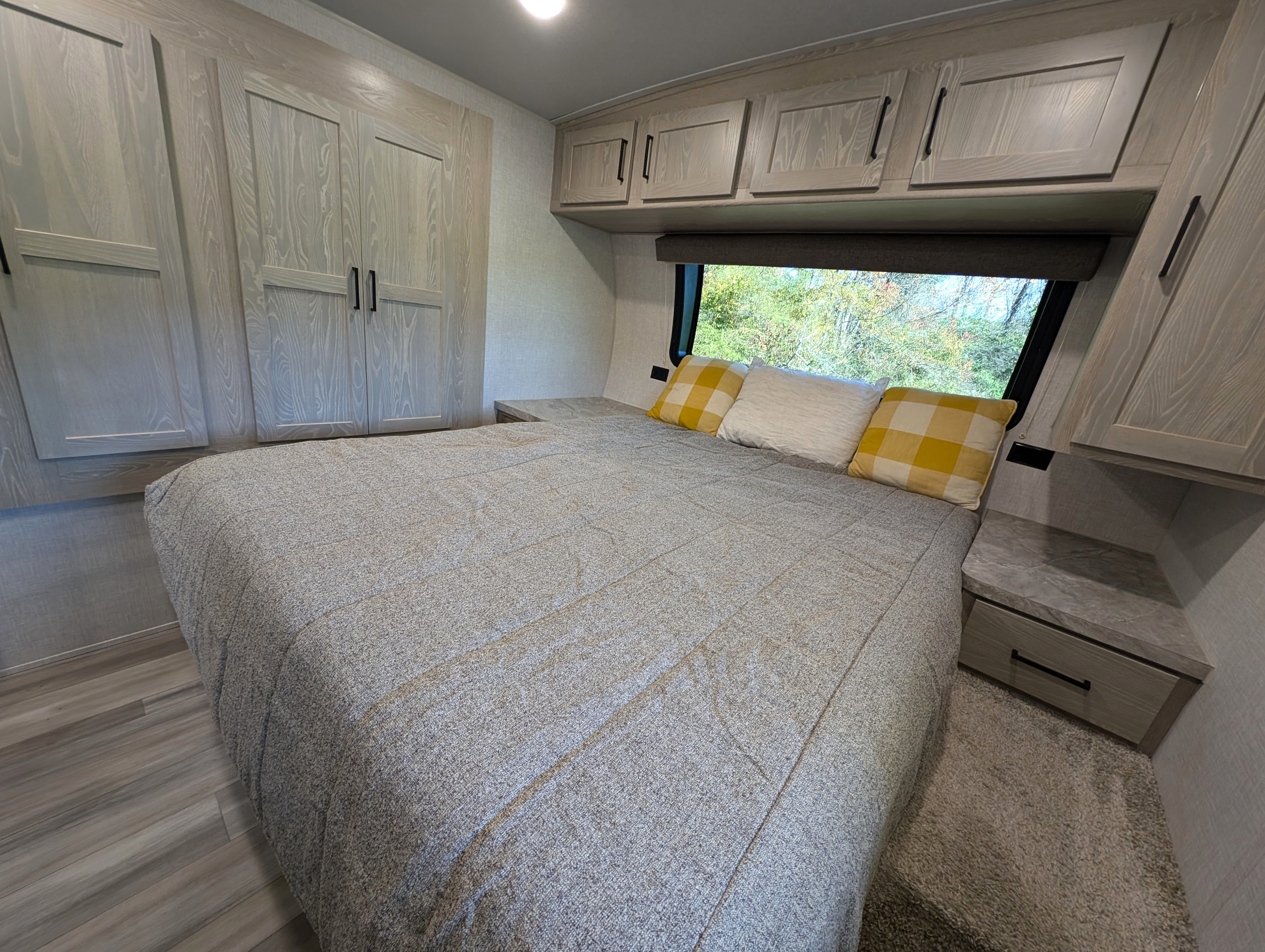 Comfortable RV rental bedroom featuring a large bed, ample storage, and a scenic window view, perfect for relaxation.. Forest River Flagstaff Micro Lite 2021
