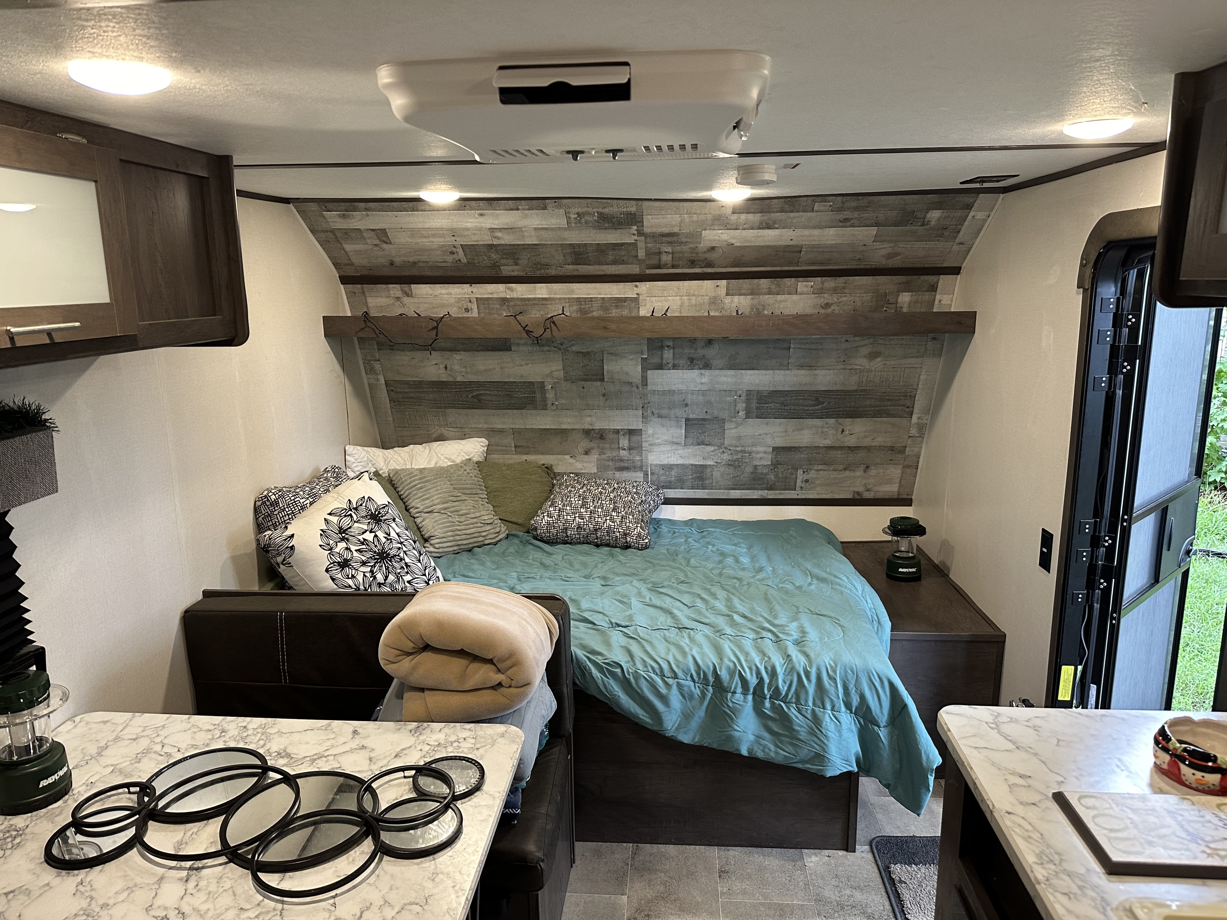 RV rental bedroom featuring a teal comforter, wooden headboard, and ample pillows, designed for compact travel comfort.. Coleman 17b 2022