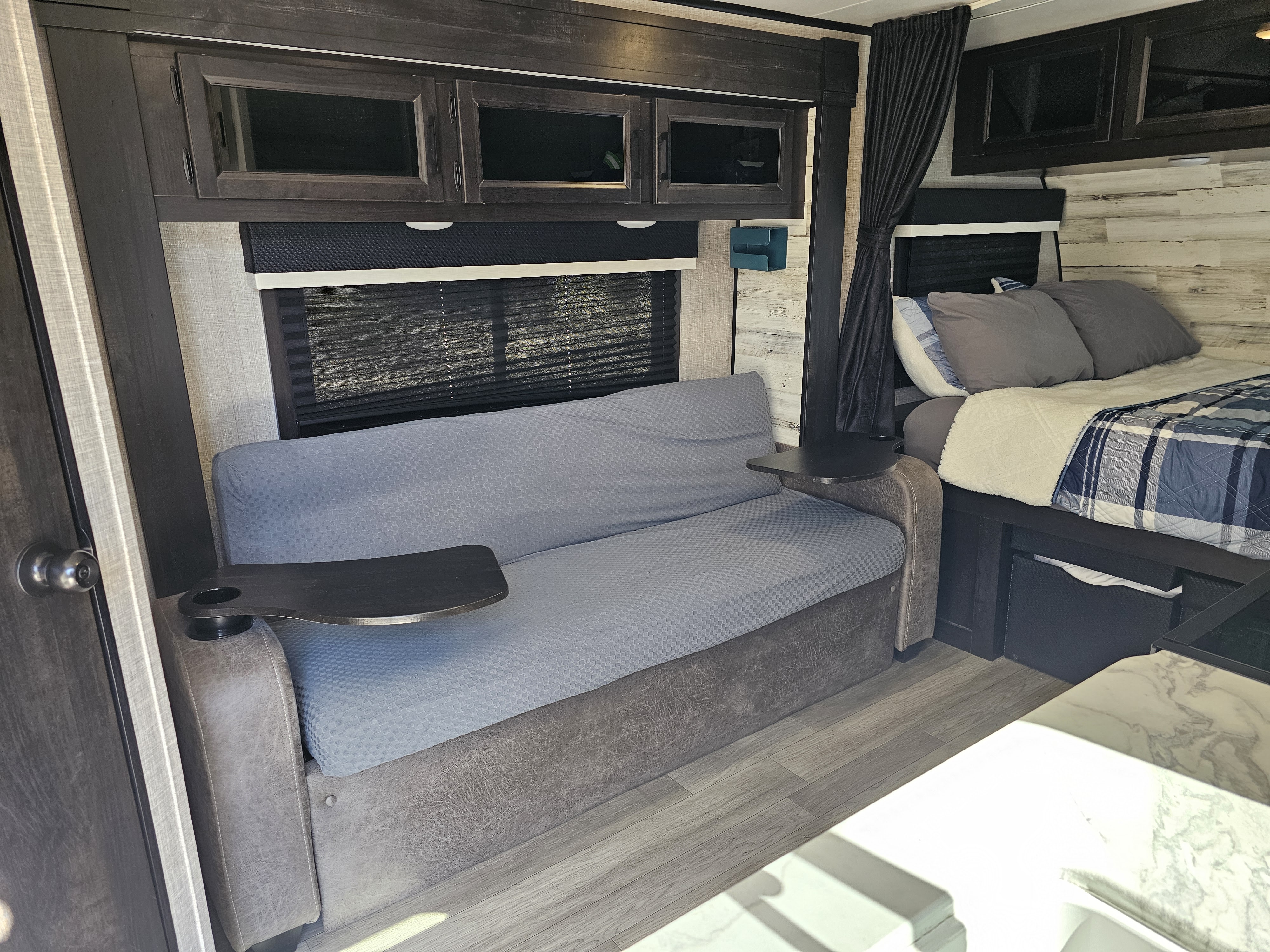 Cozy RV rental interior with a comfortable sofa and attached table, plus a neatly made bed. Perfect for relaxing and travel adventures.. Jayco Jay Feather Micro 2022