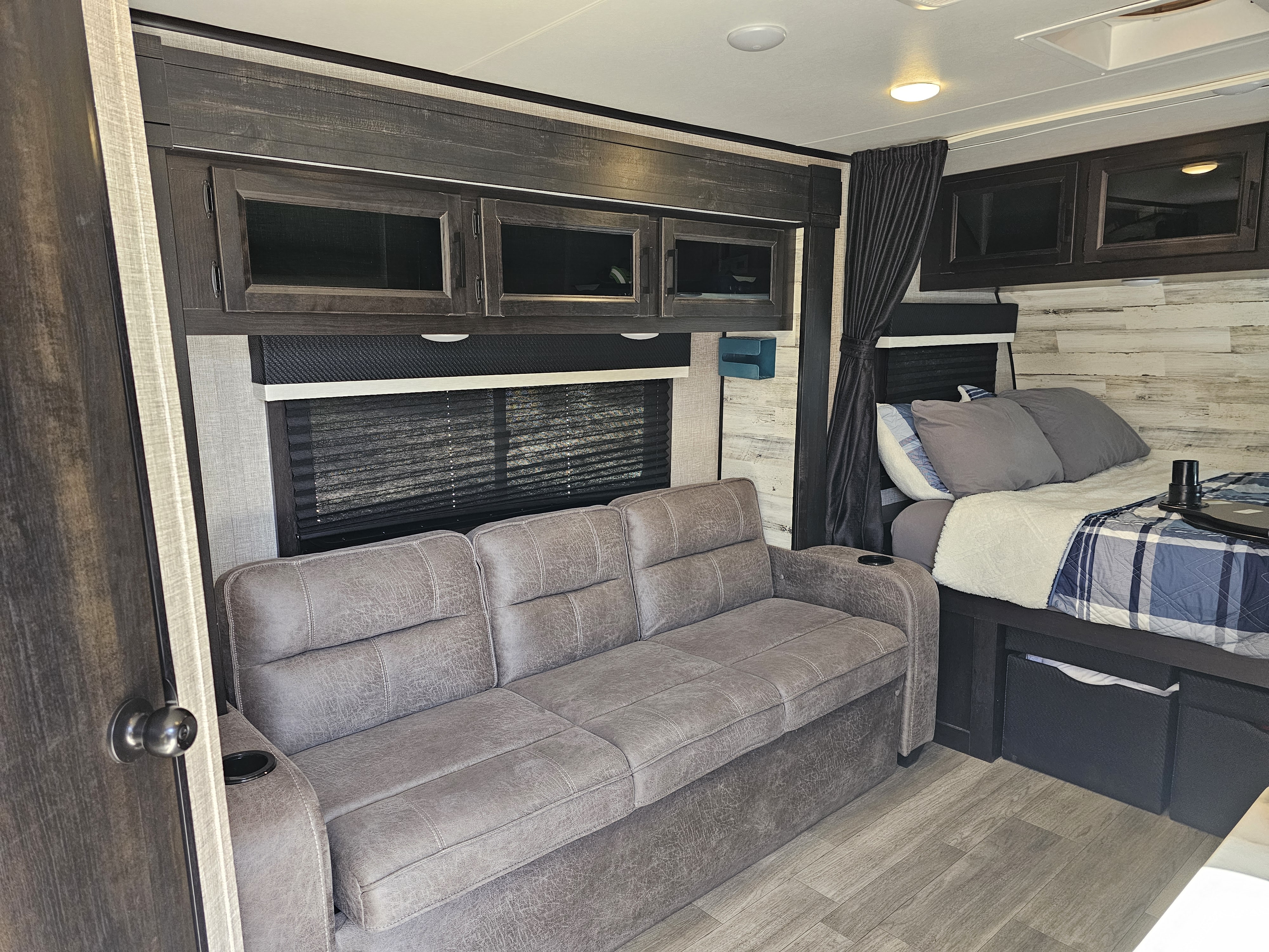Inviting RV rental interior with a plush gray sofa, cozy bed, wood accents, and convenient amenities for travel.. Jayco Jay Feather Micro 2022