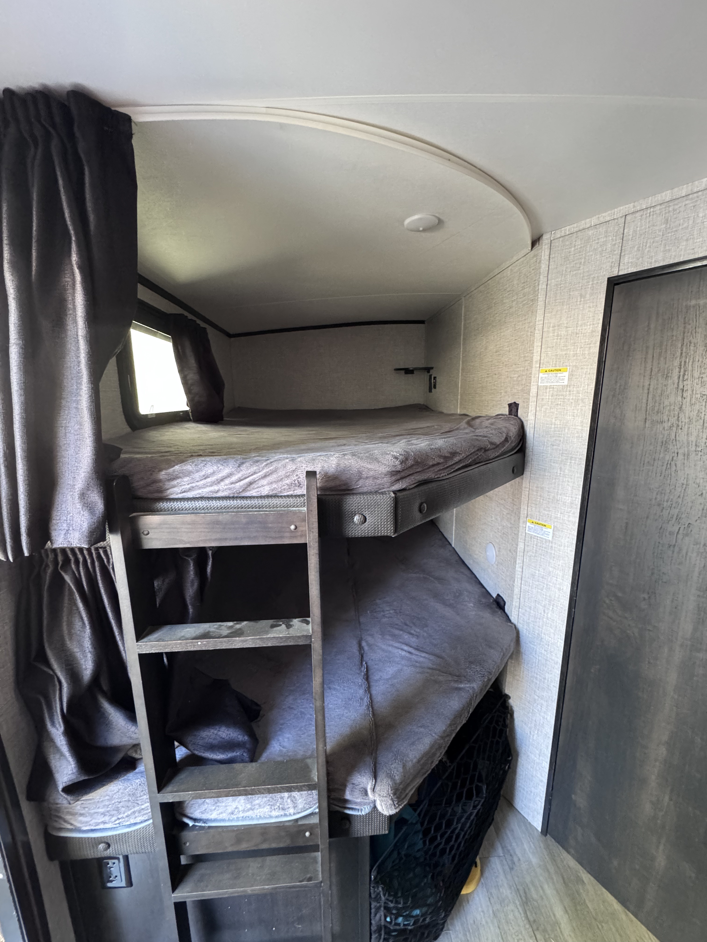 Cozy RV rental bunk beds with privacy curtains and ladder, offering comfortable sleeping in a compact space.. Jayco White Hawk 2022
