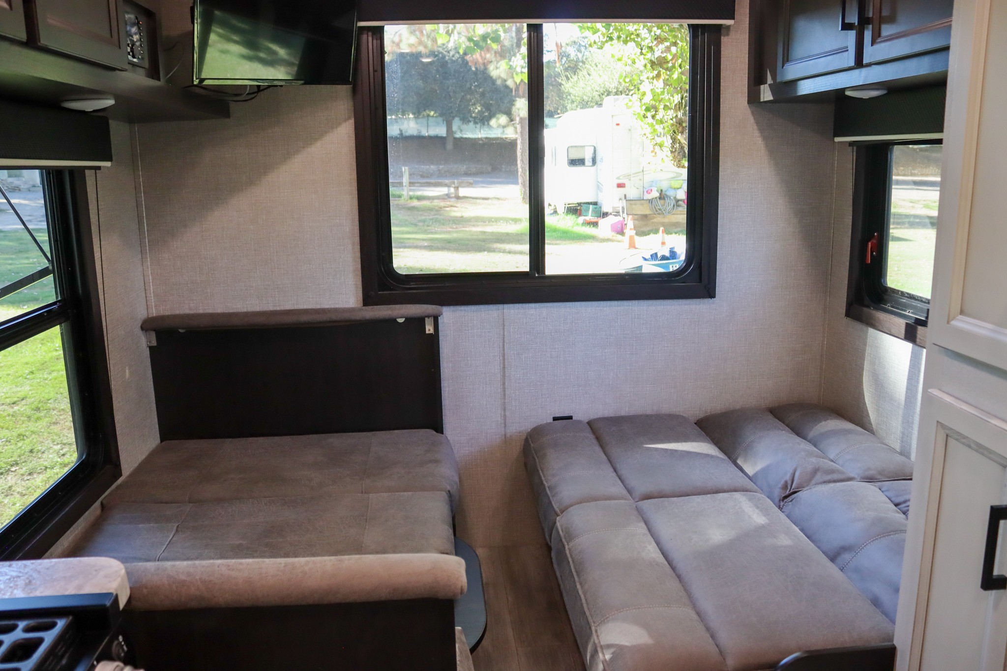 Cozy RV rental interior with a versatile dinette, convertible sofa, and large windows offering scenic views of the campground.. Jayco Jay Flight SLX Rocky Mountain Edition 2022
