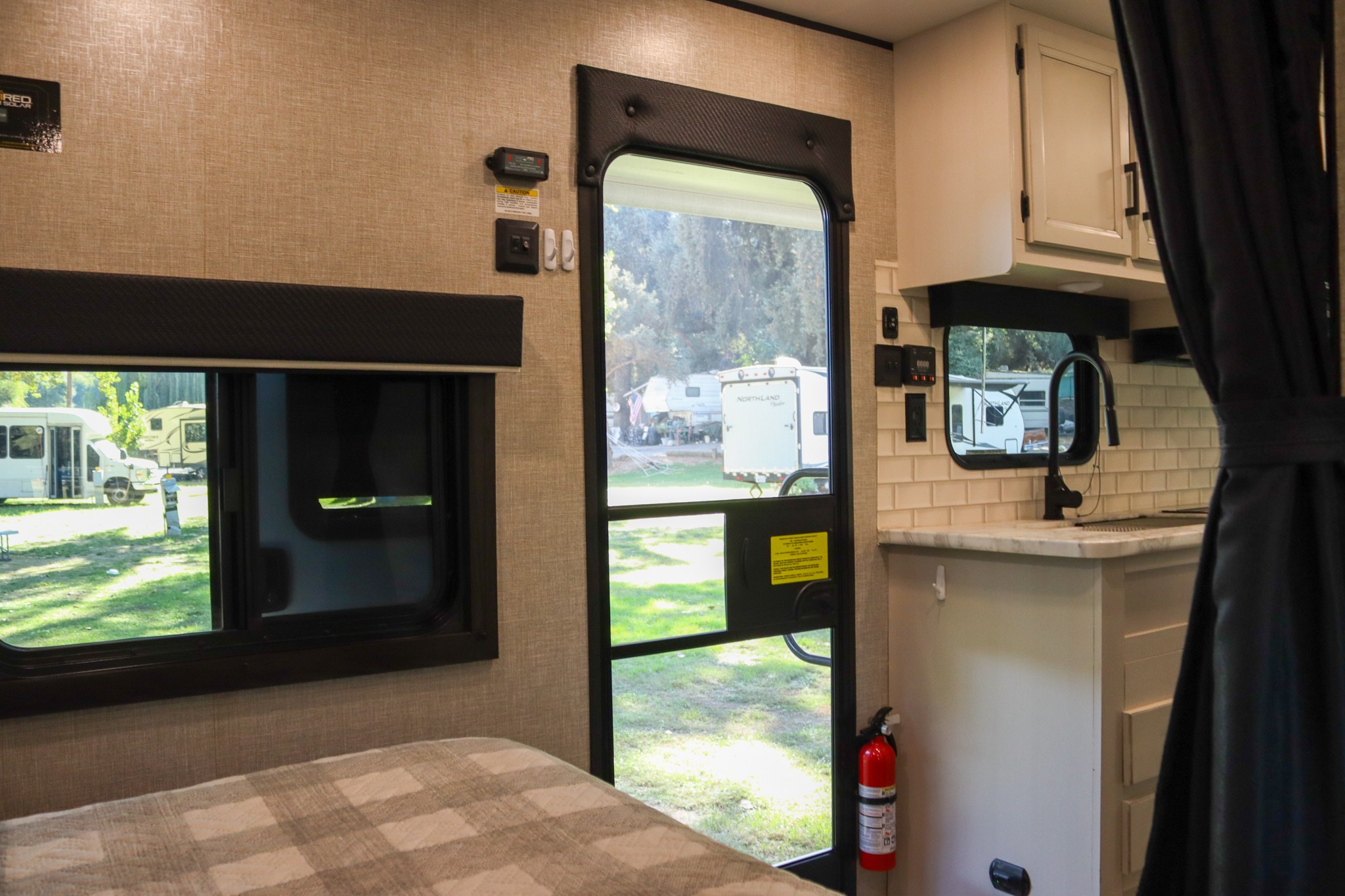 Inside an RV rental featuring a comfortable bed, functional kitchen with sink, and clear views of the outdoor campsite.. Jayco Jay Flight SLX Rocky Mountain Edition 2022
