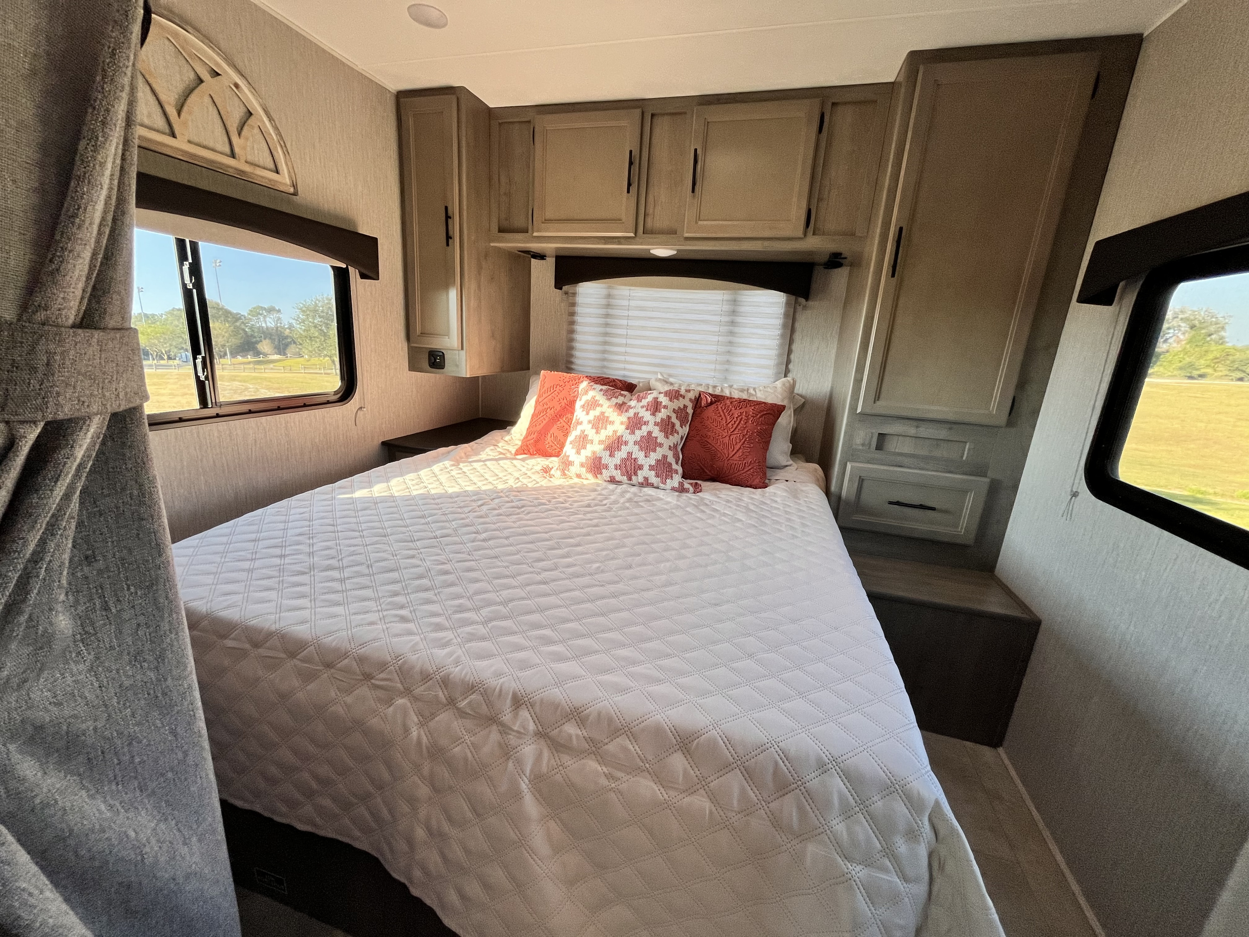 Cozy RV rental bedroom with quilted bed, built-in cabinets, and bright window view.. Coachmen Freelander 2021