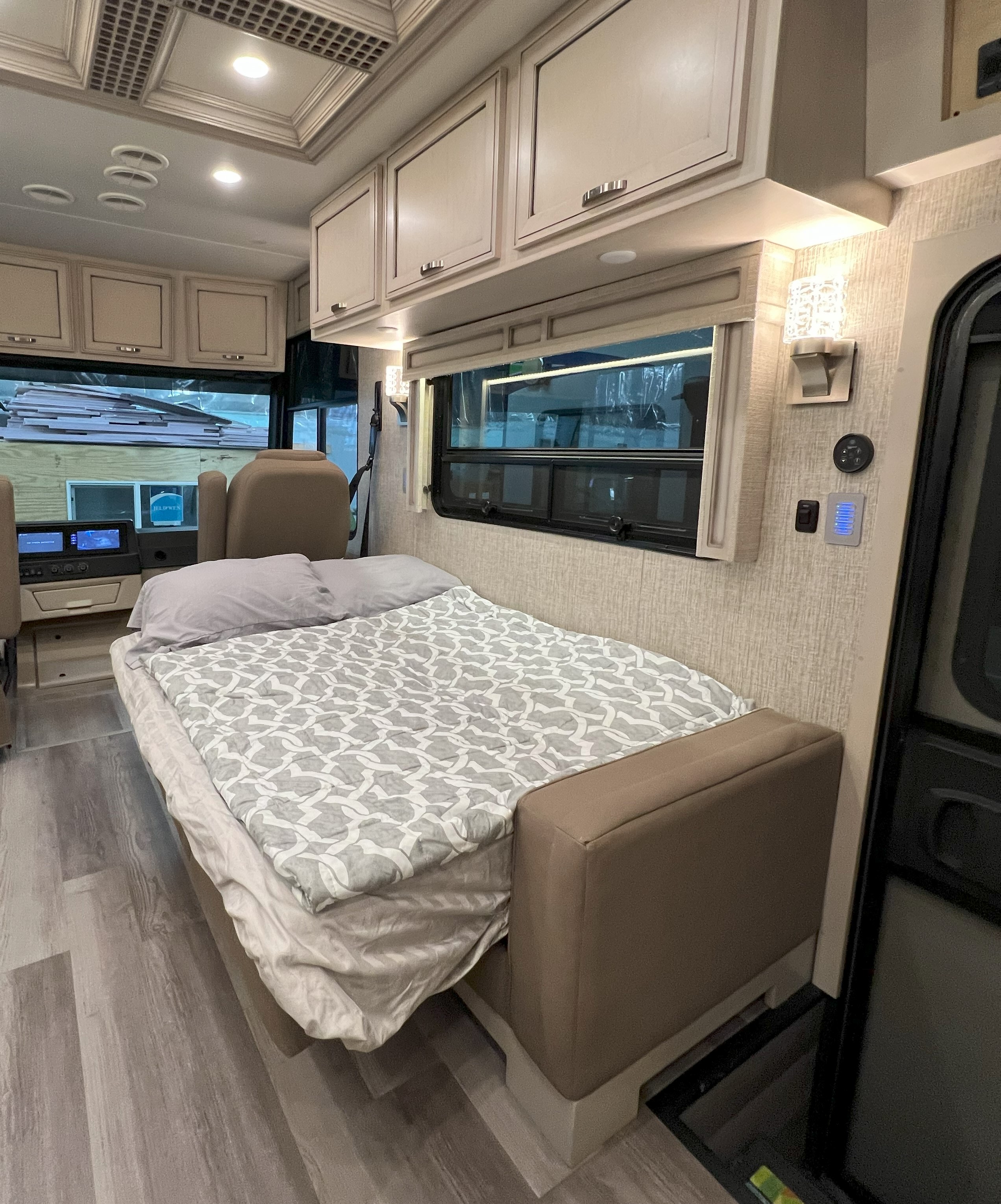 Cozy RV rental interior with a comfortable bed, overhead cabinets, and windows. Perfect for your road trip.. Holiday Rambler Admiral 2021