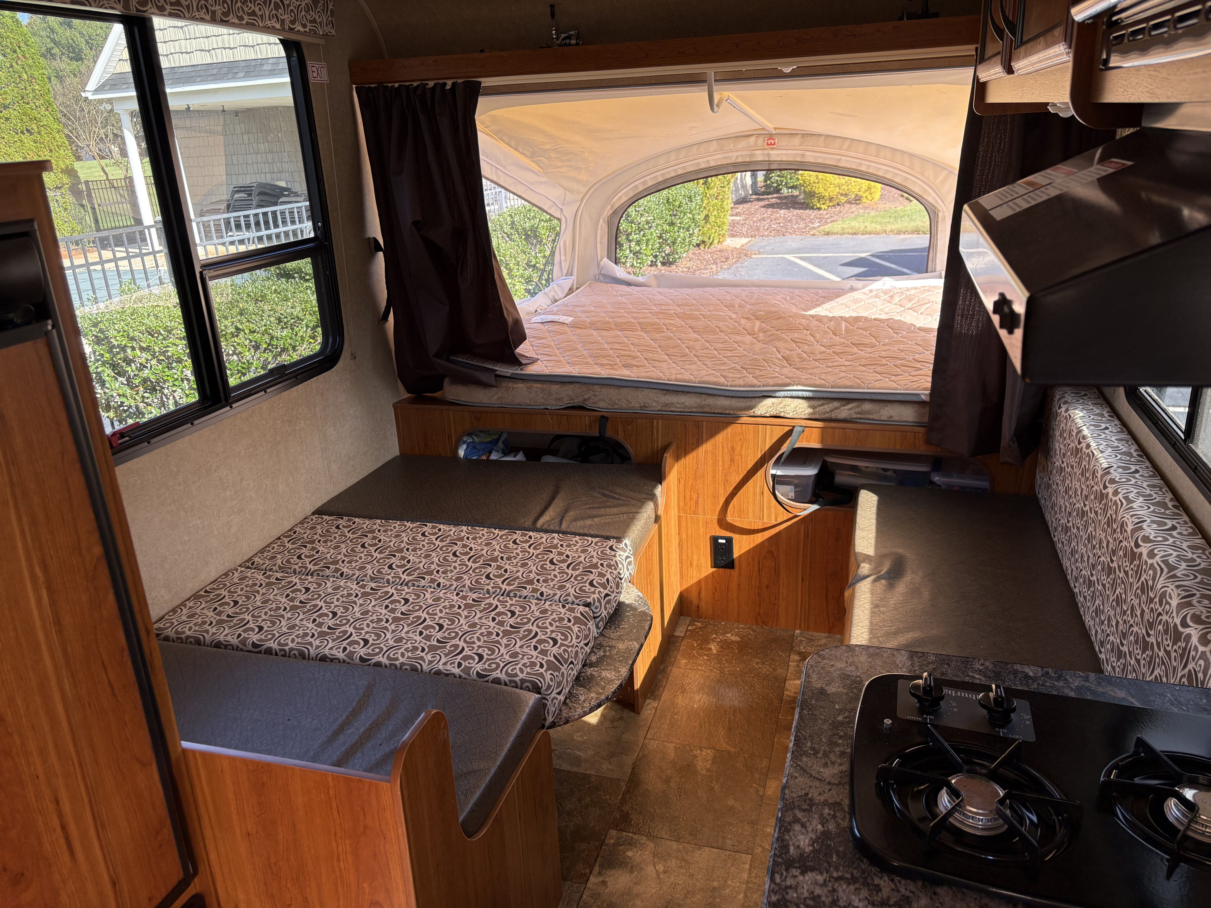RV rental interior featuring a pop-out bed, convertible dinette with patterned cushions, and kitchenette with stove.. Starcraft Launch 2016