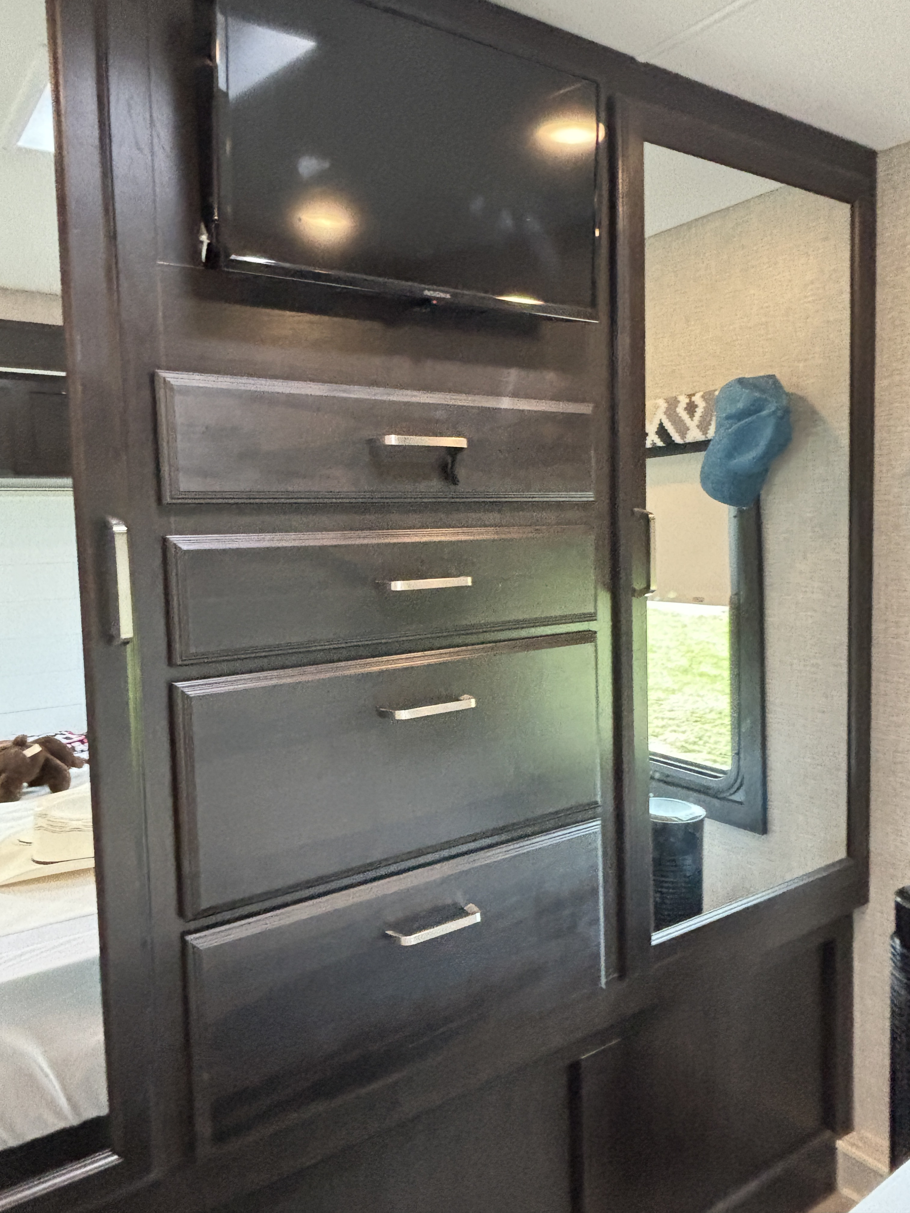 RV rental interior: dark wood dresser with TV and mirrored closet doors, offering functional storage and reflections.. Jayco Greyhawk 2022